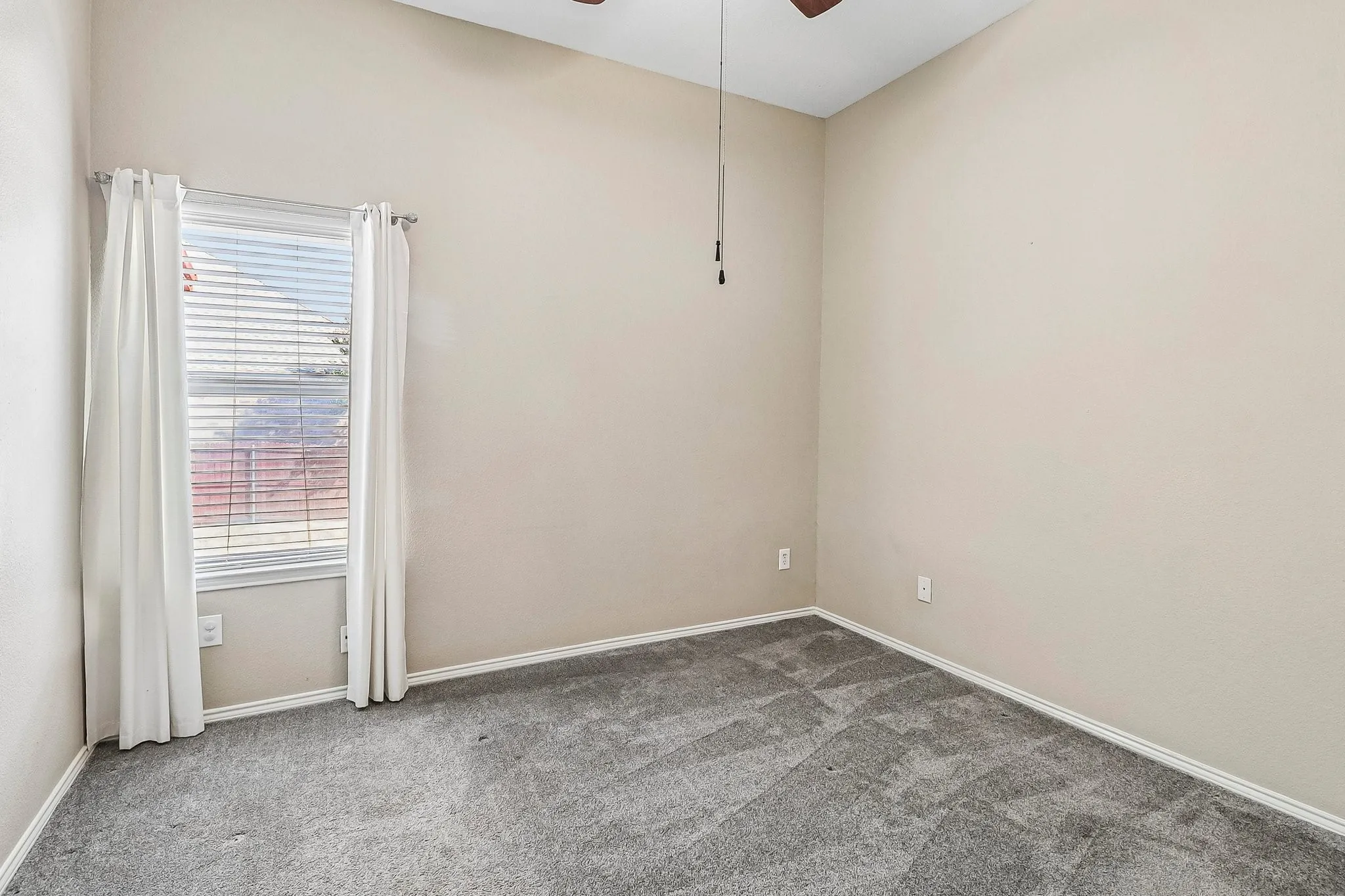 Spacious room featuring vaulted ceilings, a ceiling fan, window with blinds, and neutral carpet flooring