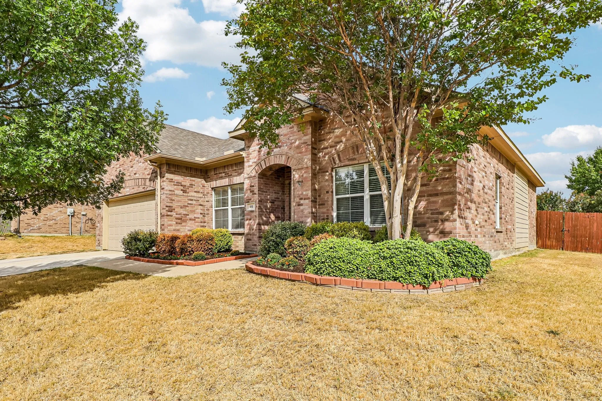Brick facade with an arched entry, two-car garage, and fenced backyard