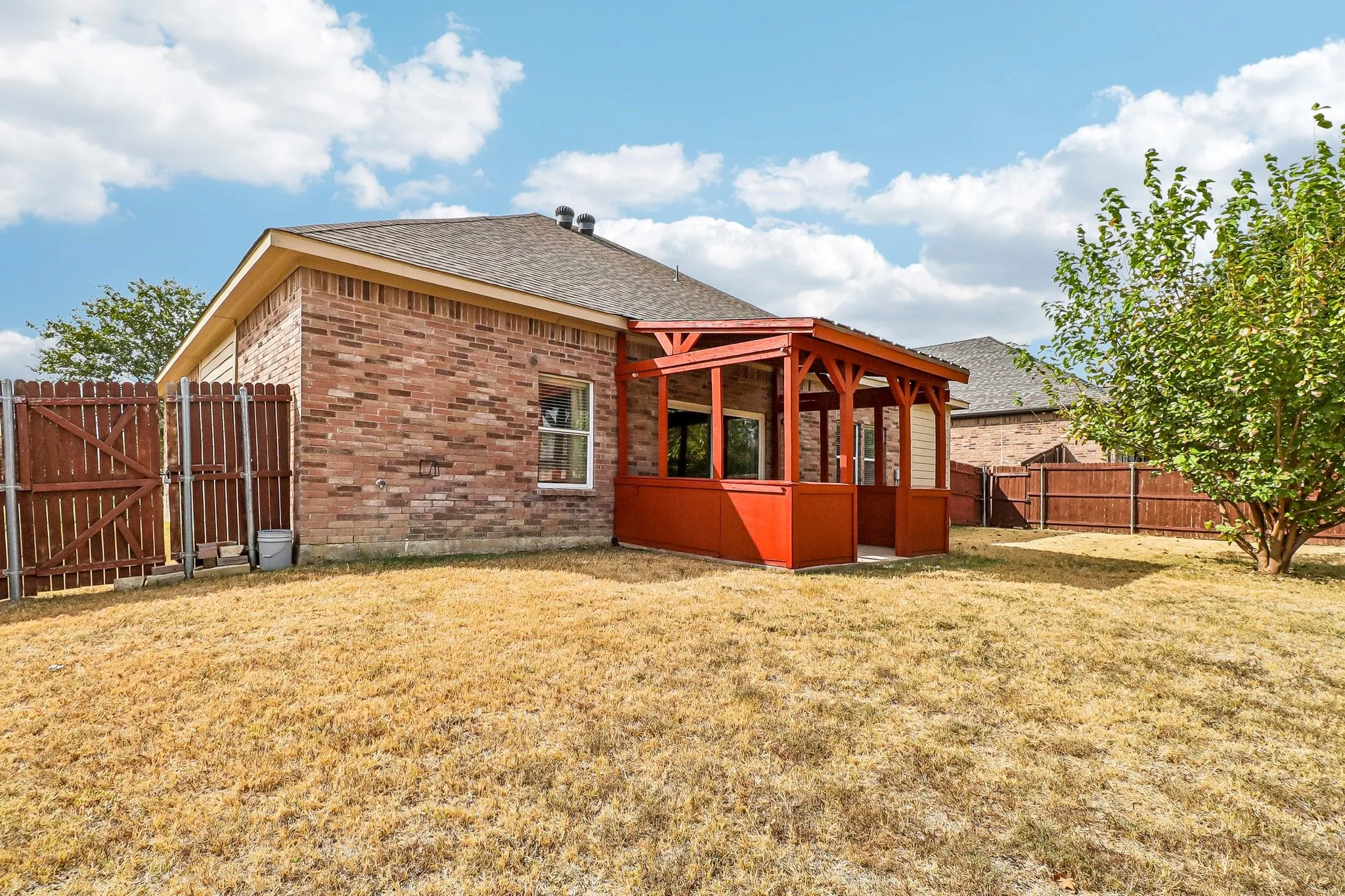 Brick exterior, covered patio structure, fenced property, established tree