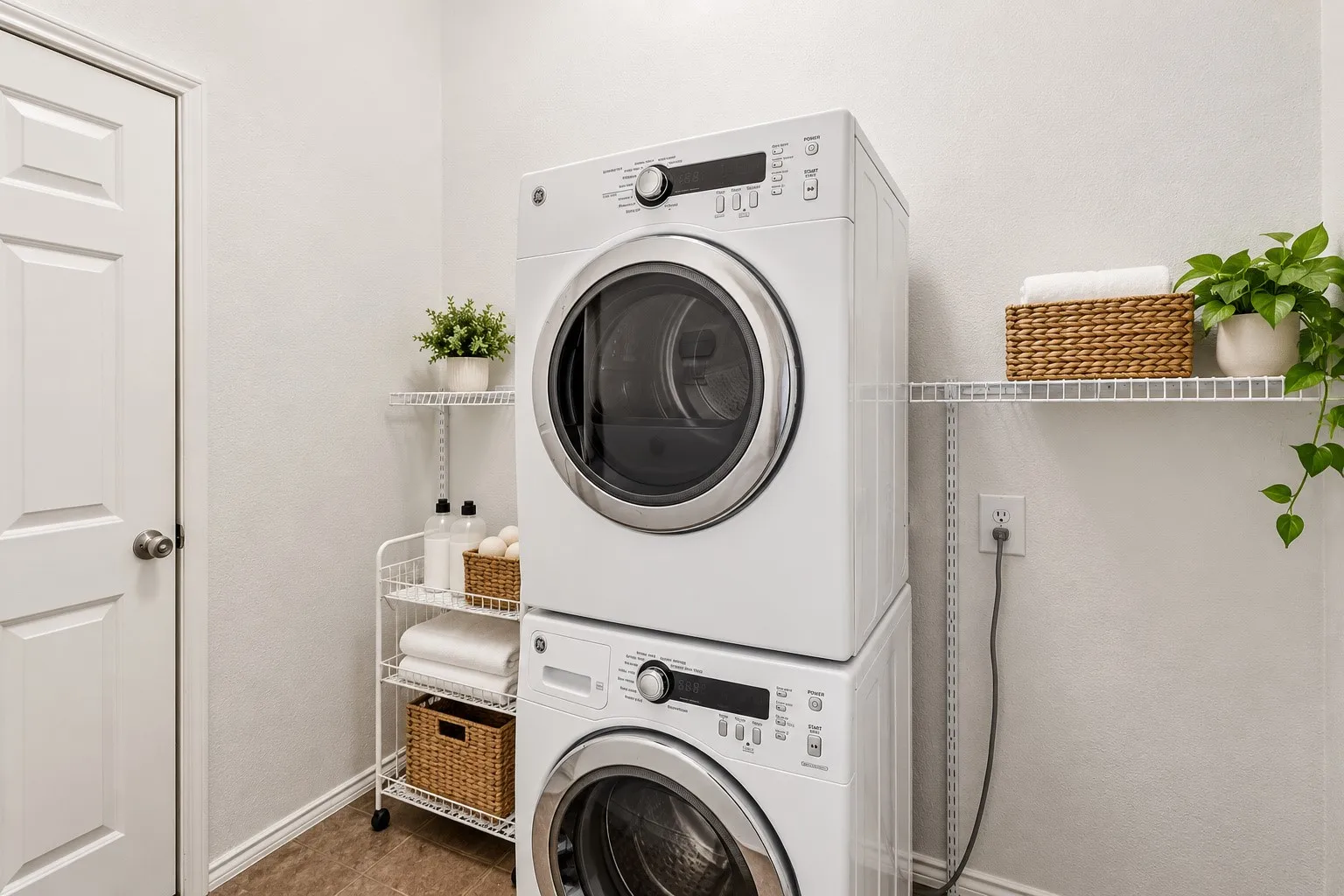 Stackable washer and dryer appliances, wall-mounted shelving, wood-finish flooring, and a paneled door