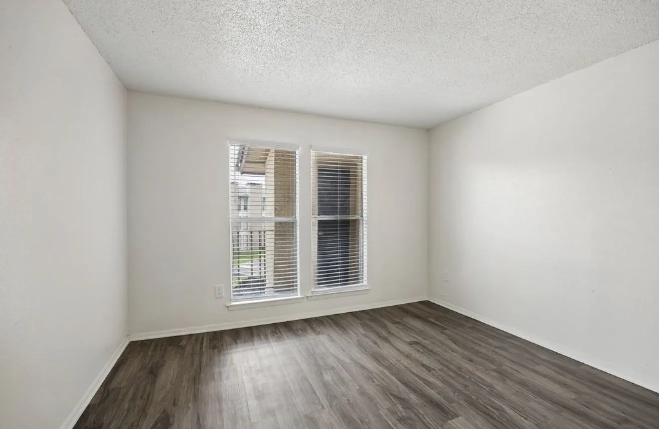 Wood-finish flooring, white walls, and a window with blinds