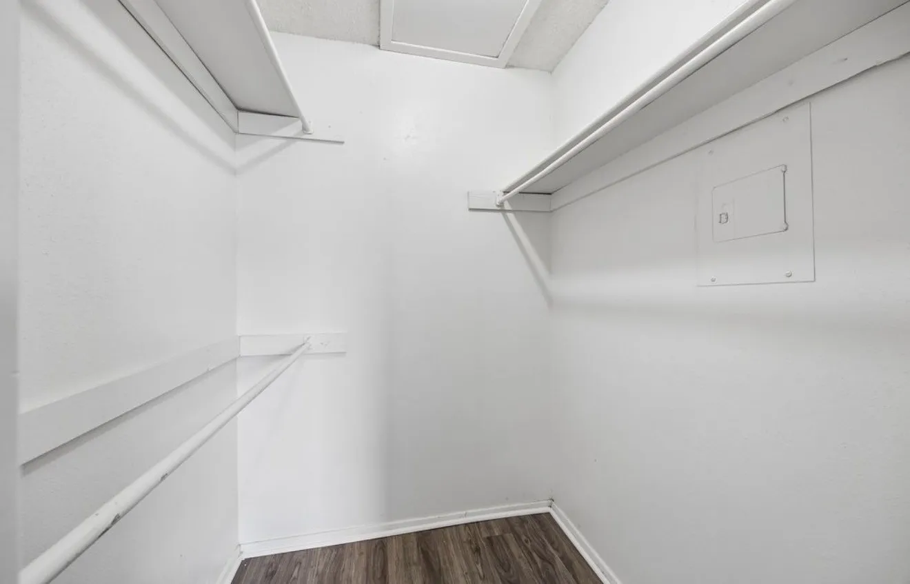 Built-in shelving and hanging rods, wood-finish flooring, and white painted walls