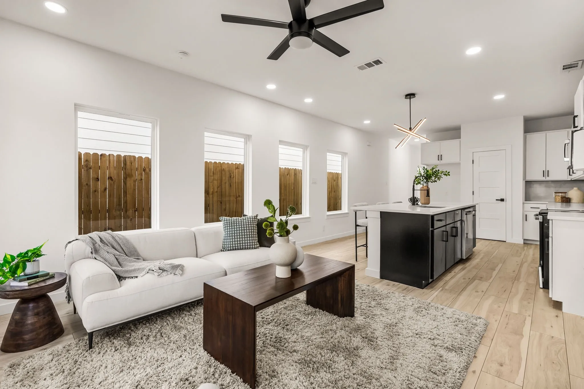 Open-concept living space with light wood-finish flooring, recessed lighting, and a modern ceiling fan