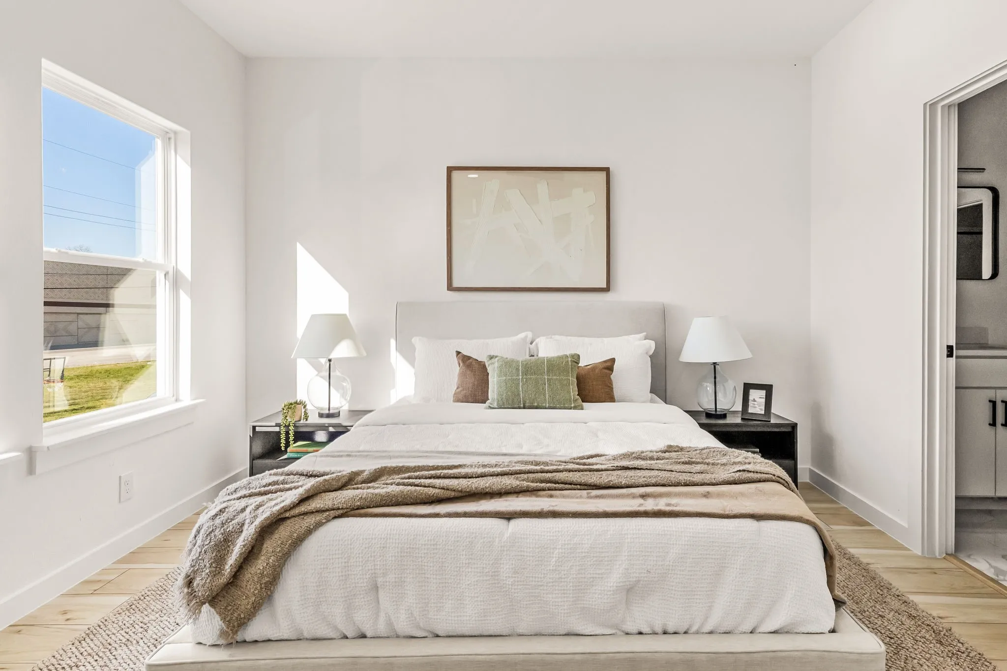 Room featuring wood-finish flooring, a double-hung window, and an open doorway to a bathroom with a vanity