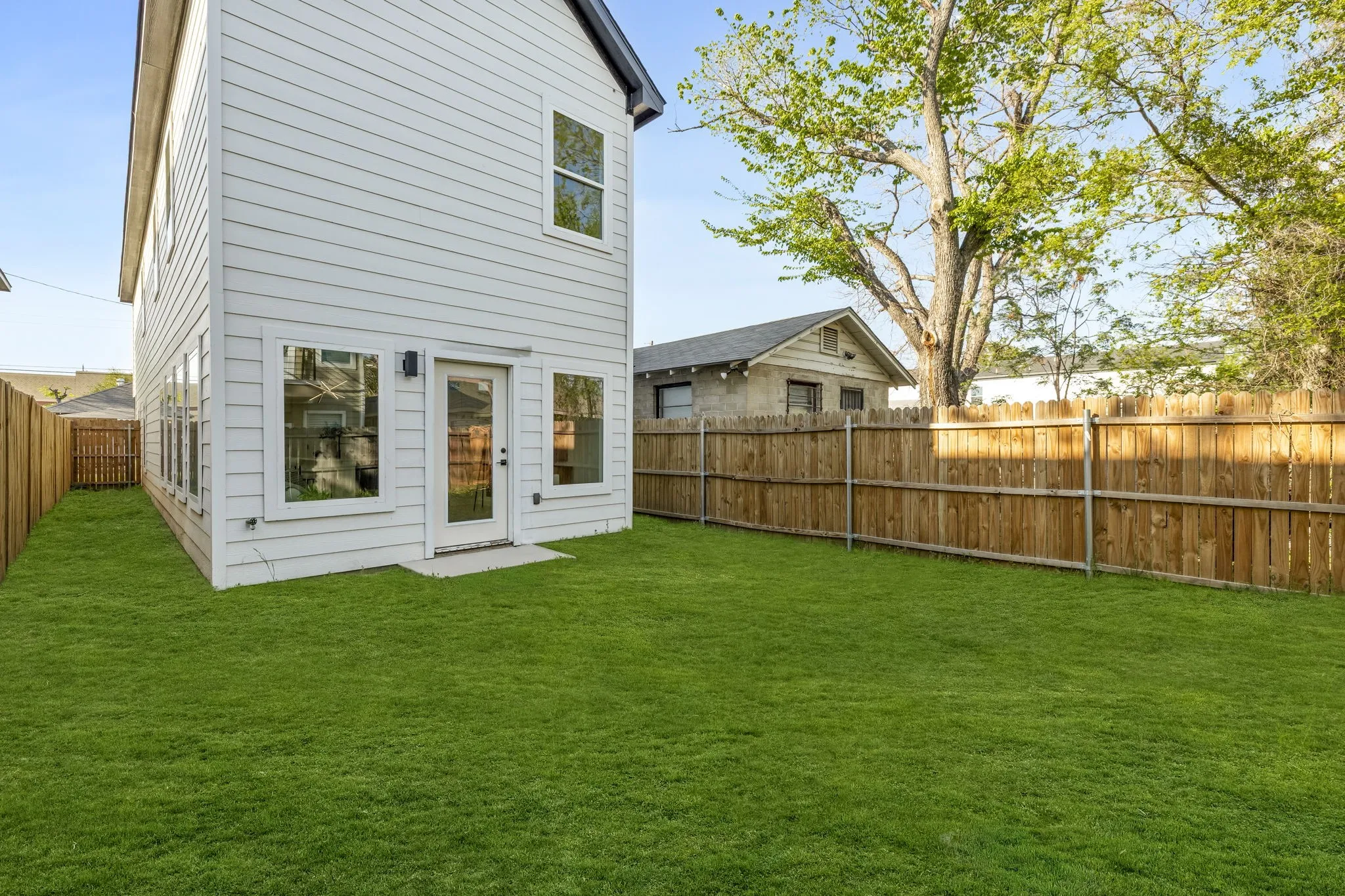 Expansive grassy yard with wood fencing and a concrete patio
