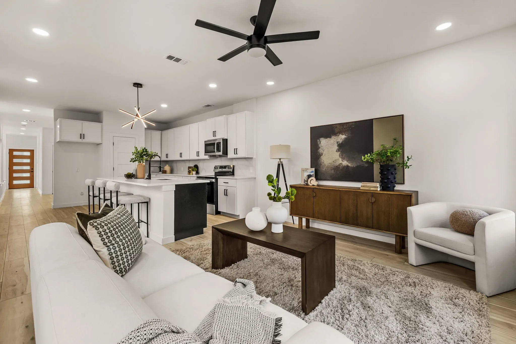 Open-concept living space with wood-finish flooring, recessed lighting, and a ceiling fan