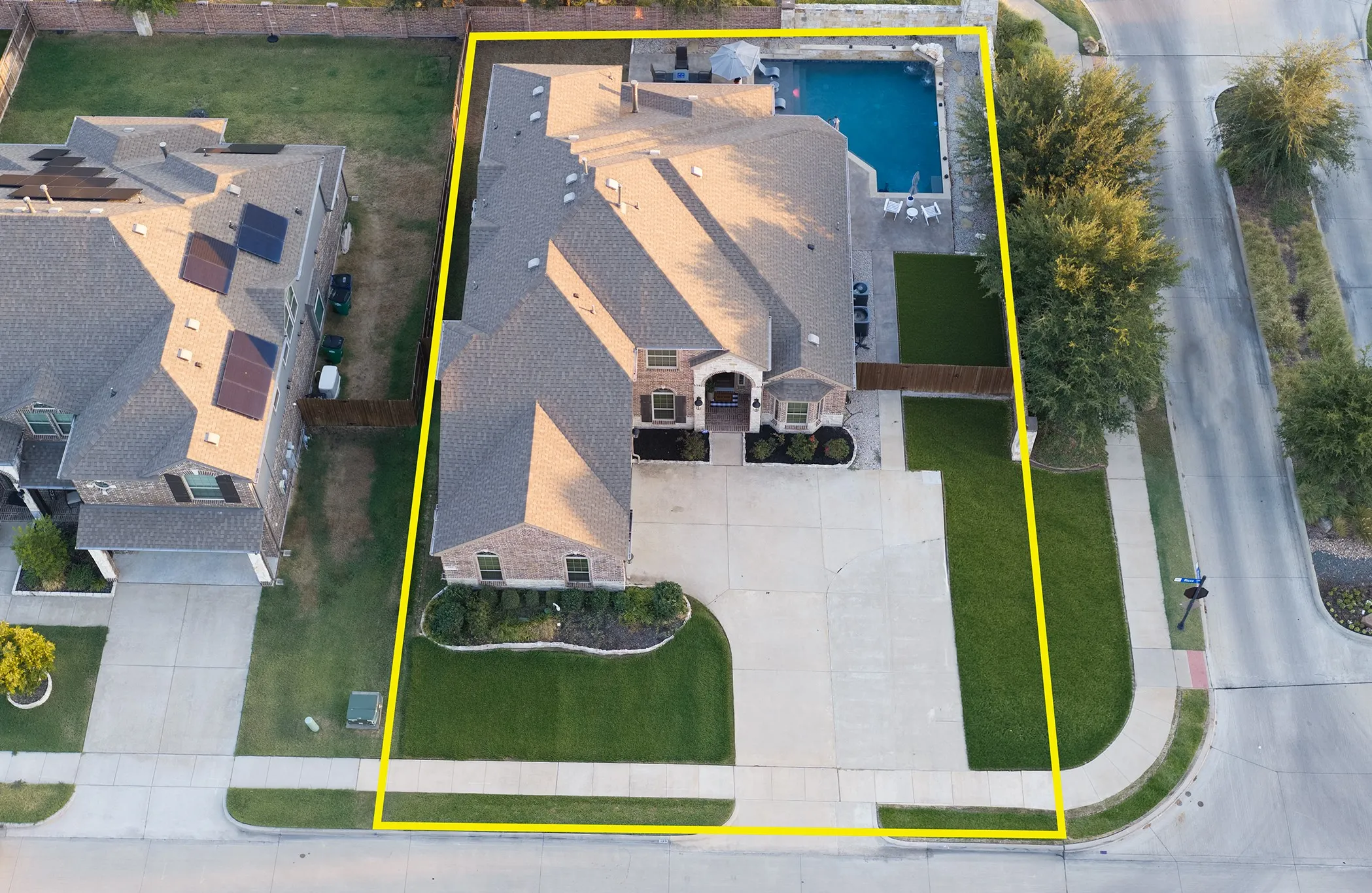 Expansive brick residence with a multi-gabled roofline, featuring a private swimming pool, artificial turf area, and a large concrete driveway