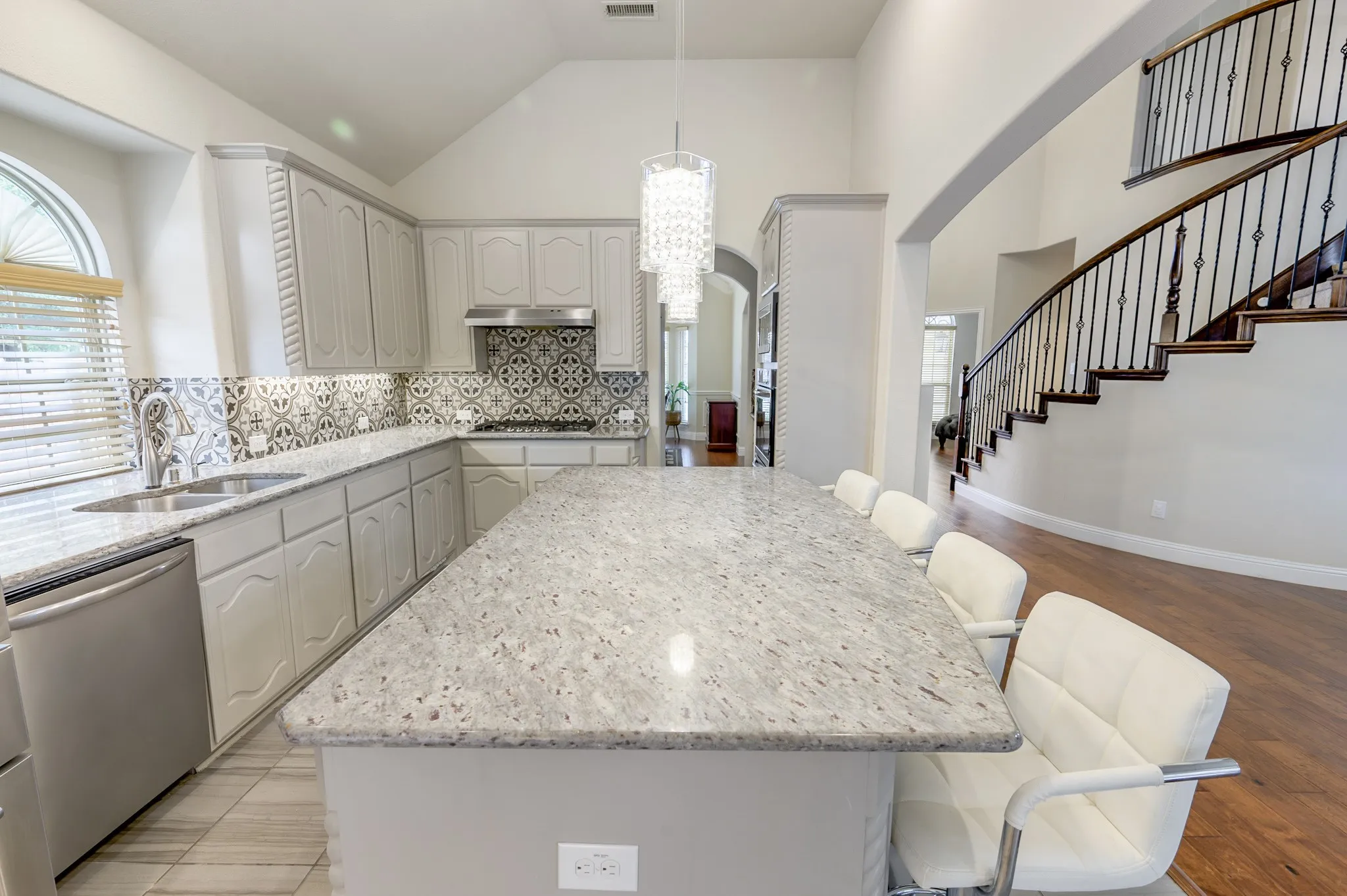 Kitchen island with stone countertop, stainless steel appliances, and decorative tile backsplash