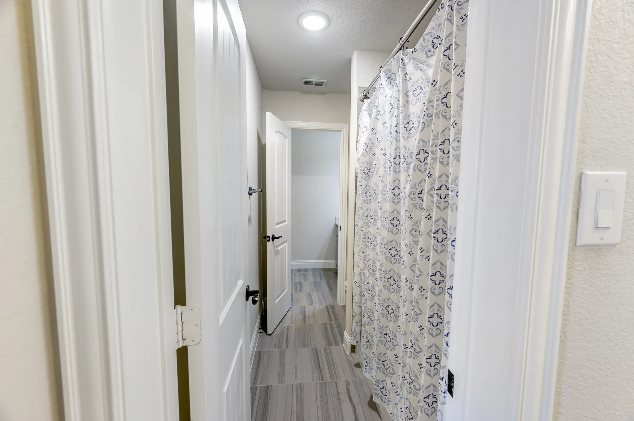 Hallway with grey rectangular tile flooring and recessed ceiling lighting