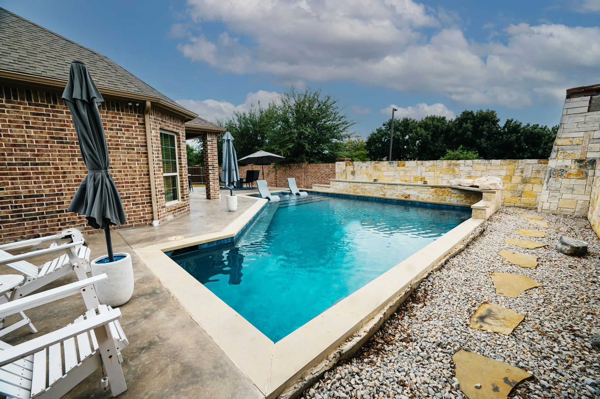 Brick exterior, geometric swimming pool, stone accent wall, waterfall feature, flagstone path