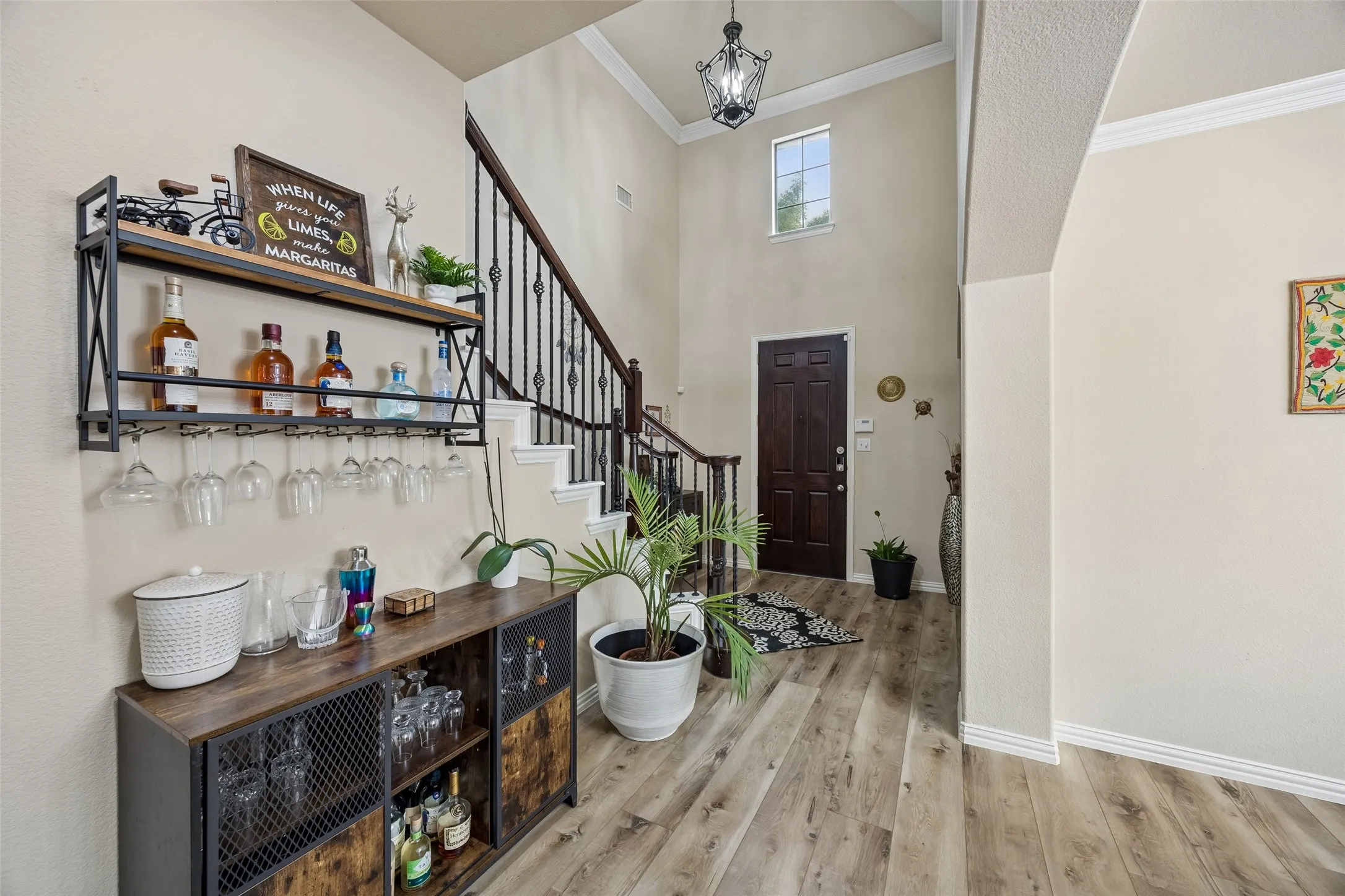 Two-story foyer with a dark wood-finish entry door, wood-finish flooring, and crown molding