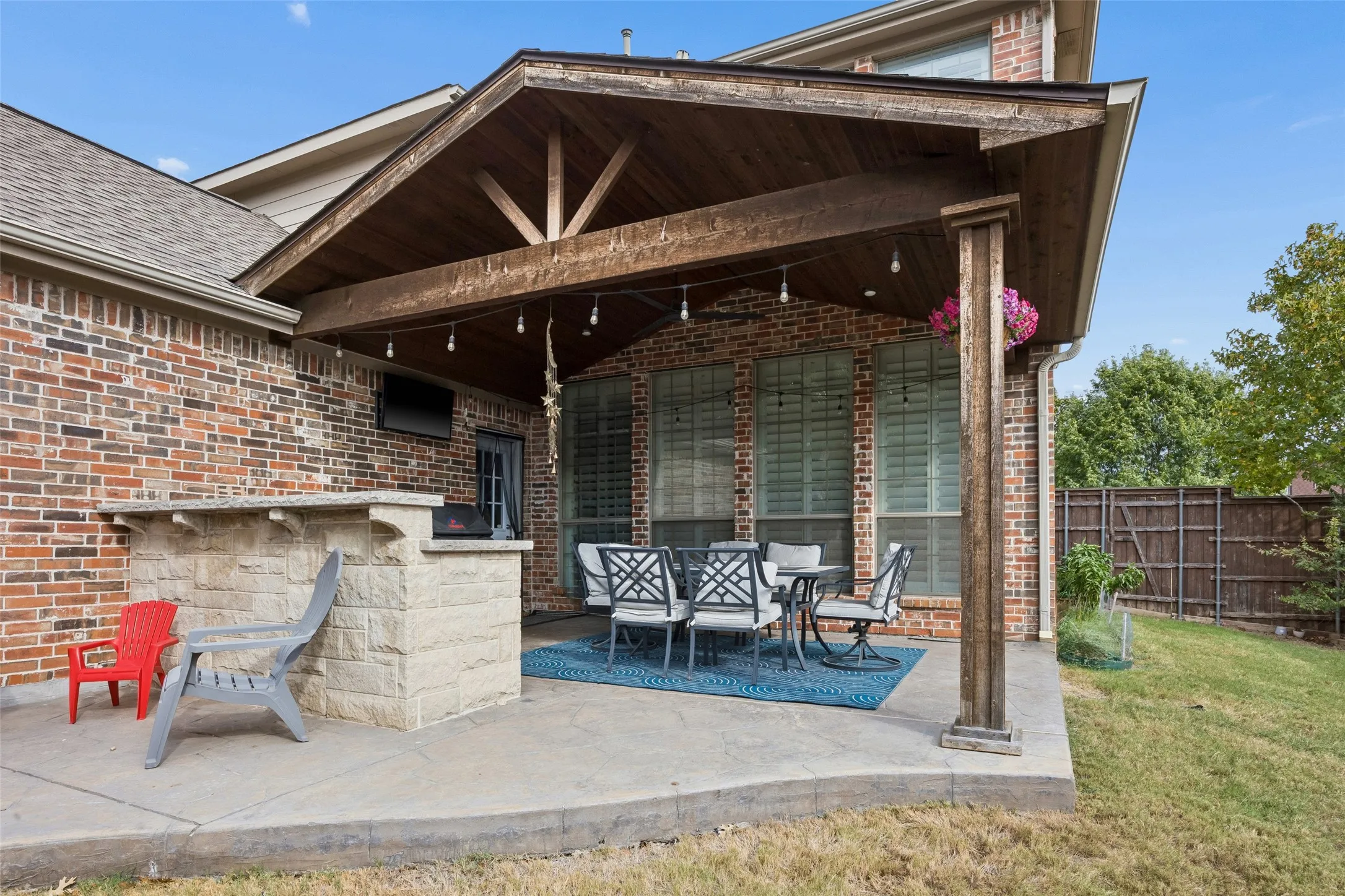 Covered patio with a wood-plank ceiling, exposed wood beams, and a built-in stone bar