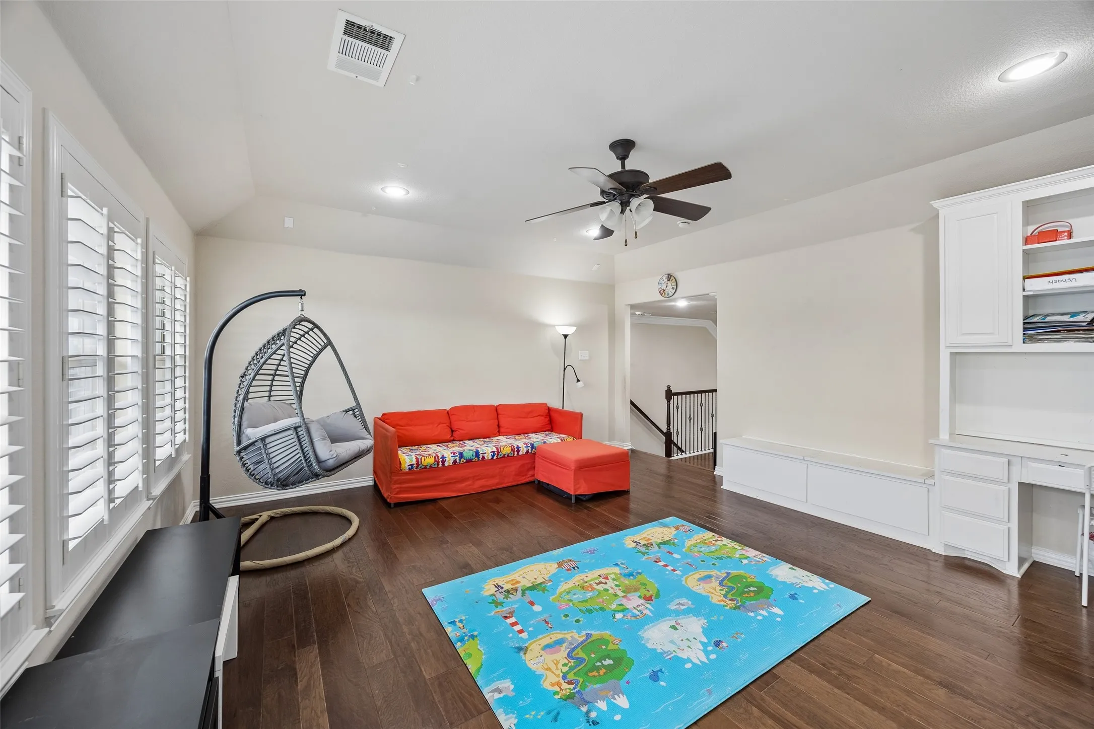 Wood-finish flooring, recessed lighting, ceiling fan, white window shutters, and built-in white cabinetry with desk