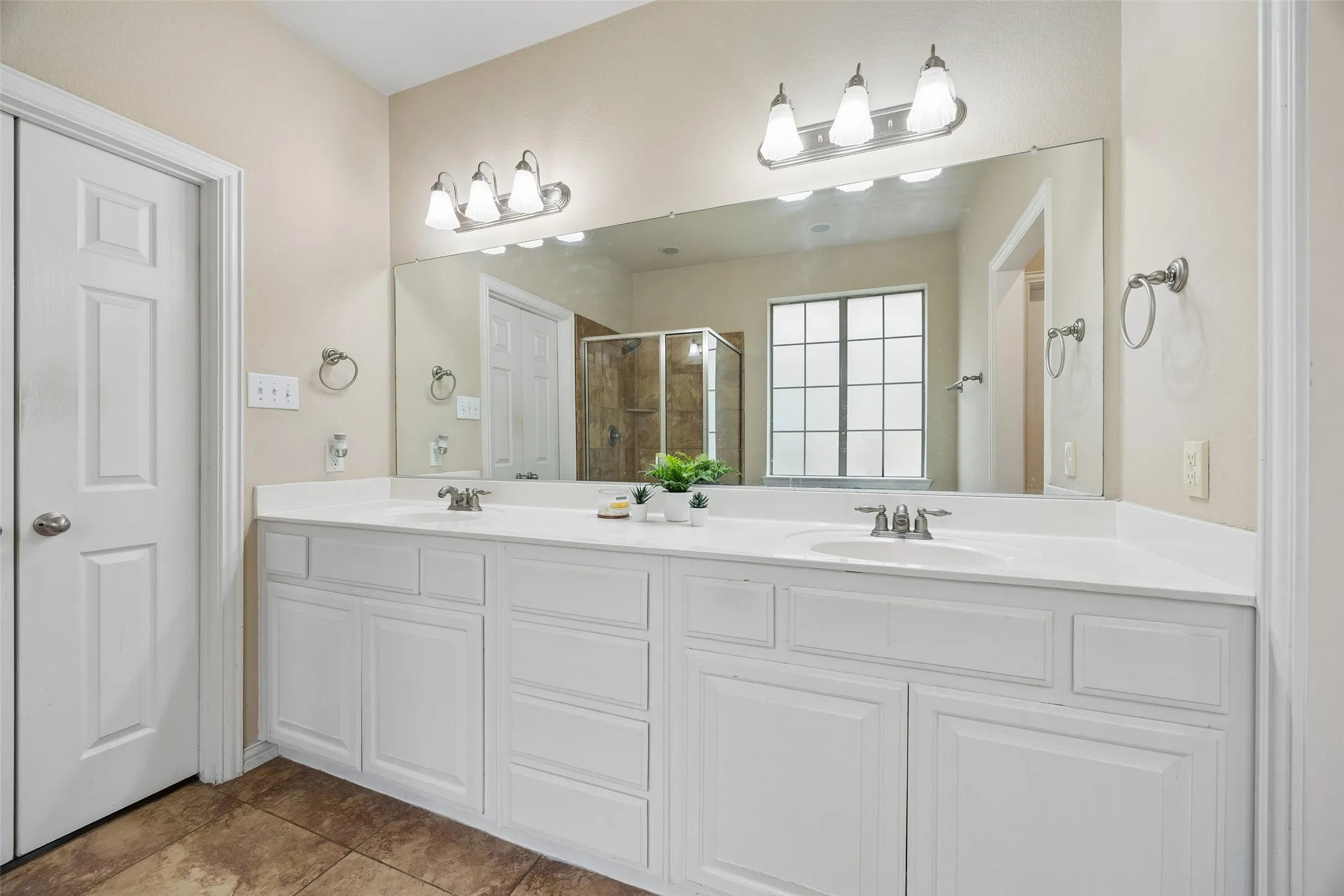 Dual vanity with white cabinetry, integrated sinks, brushed nickel fixtures, and a large wall-mounted mirror