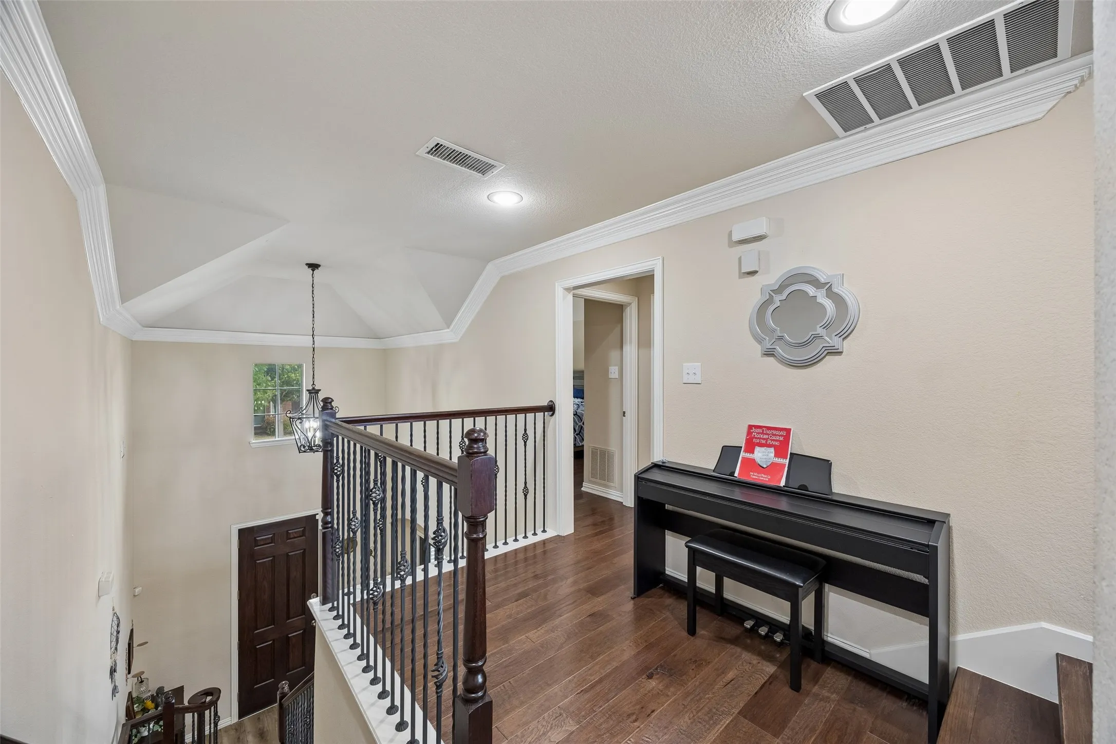 Wood-finish flooring, recessed lighting, crown molding, iron balusters, and a vaulted ceiling