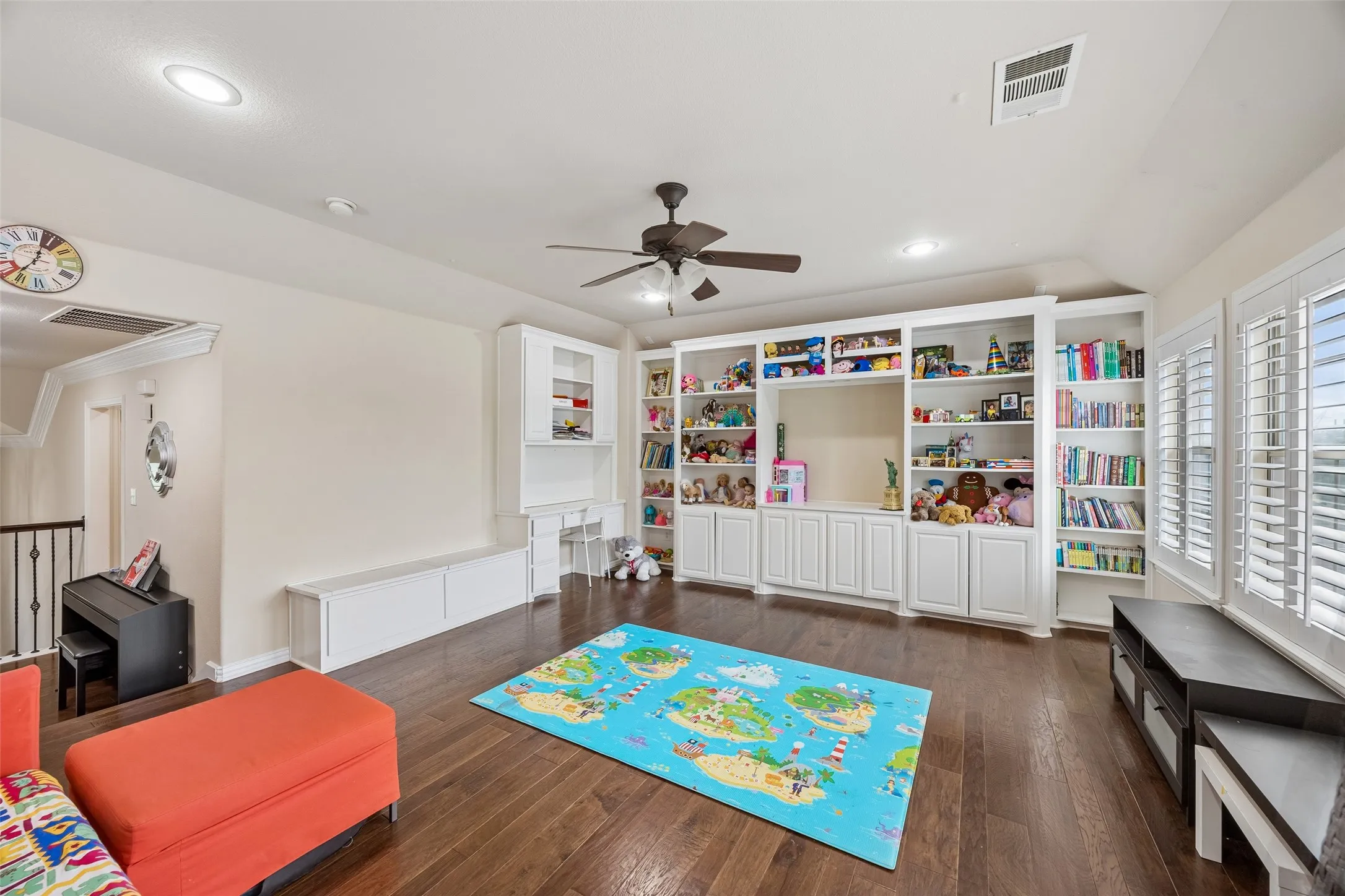 Hardwood-finish flooring, built-in shelving, white plantation shutters, recessed lighting, and a ceiling fan