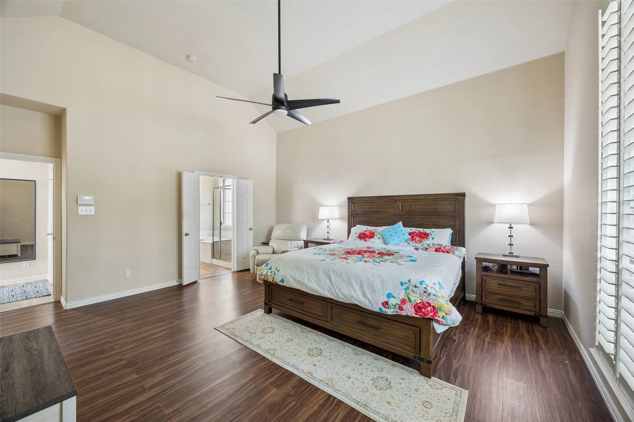 Vaulted ceiling with a ceiling fan, wood-finish flooring, plantation shutters, and double doors