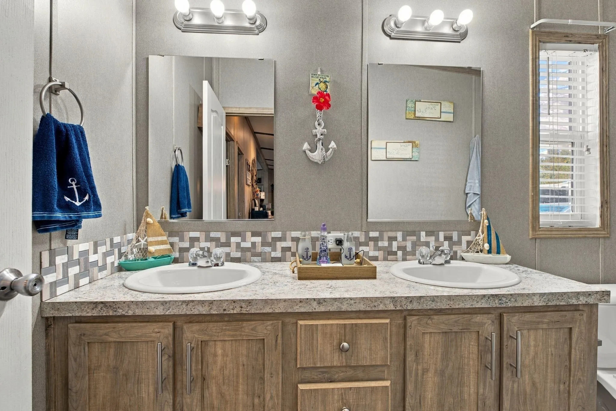 Dual vanity with integrated sinks, wood-finish cabinetry, and a patterned tile backsplash