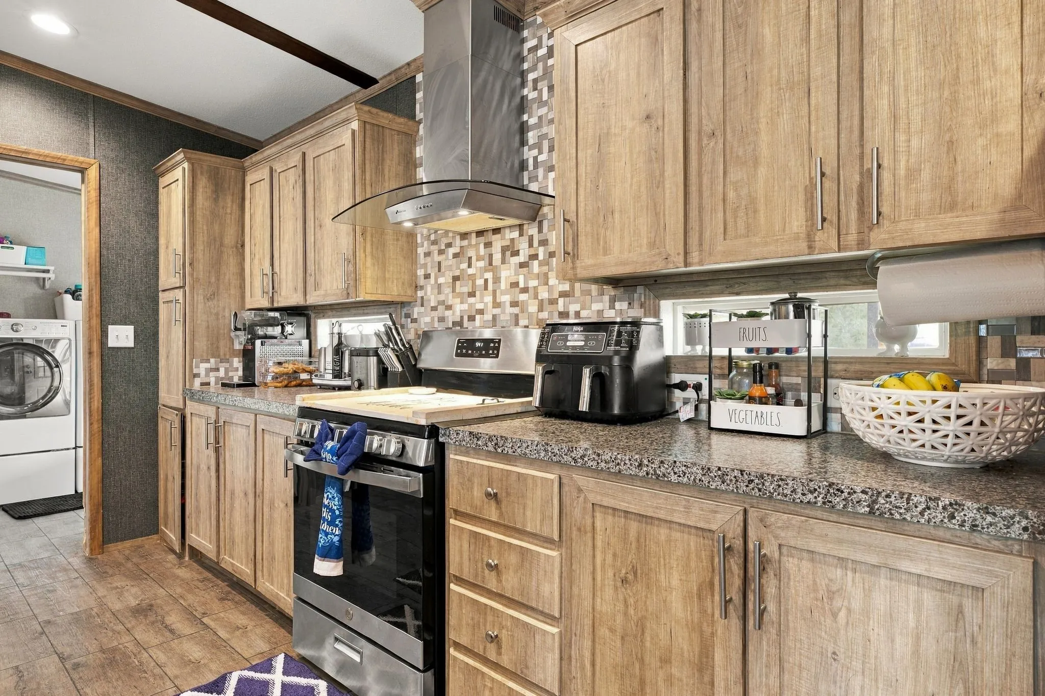 Kitchen featuring wood-finish cabinetry, speckled countertops, and a tiled backsplash