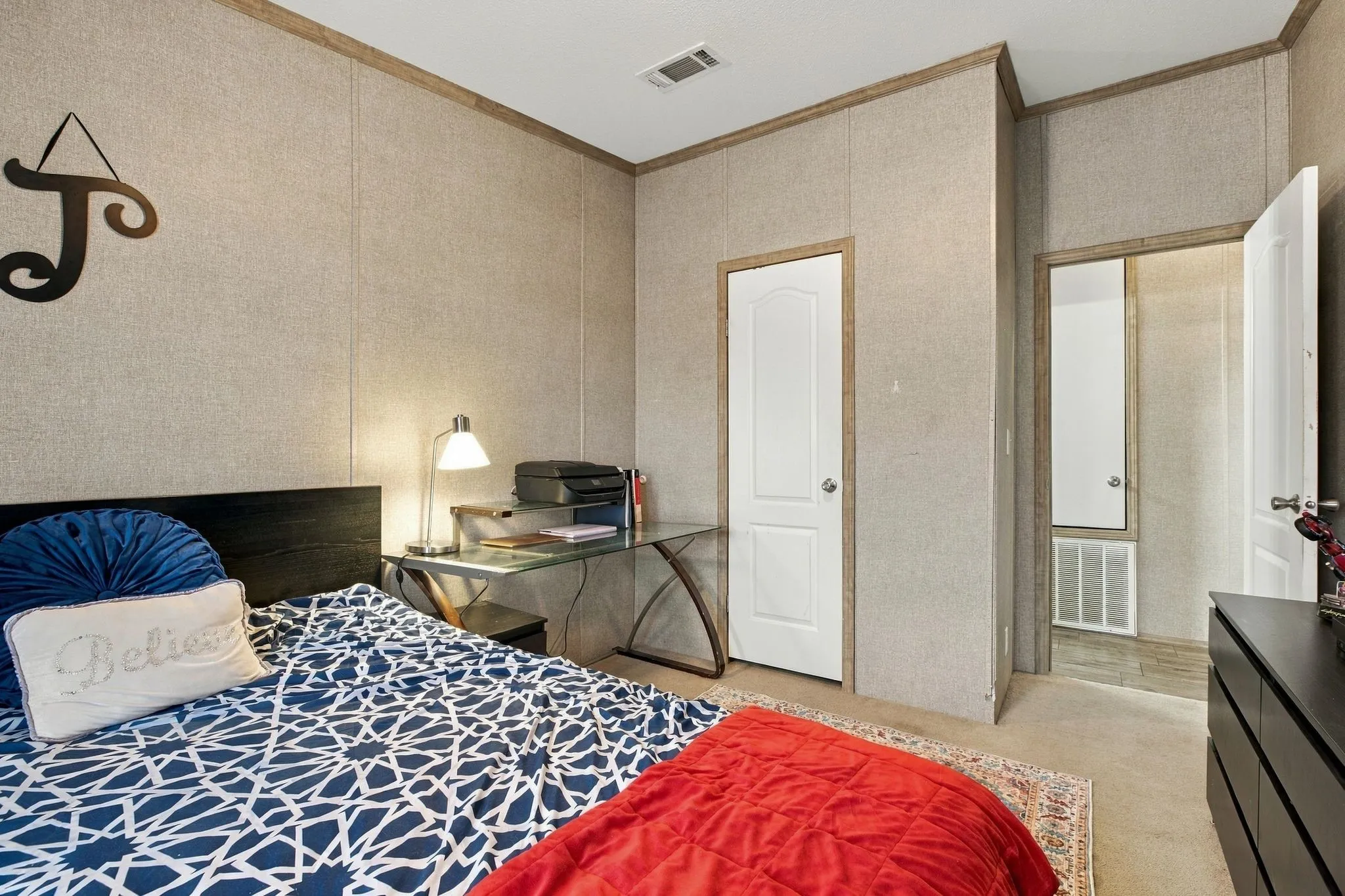 Carpeted flooring, paneled walls, white interior doors, and a built-in overhead air vent