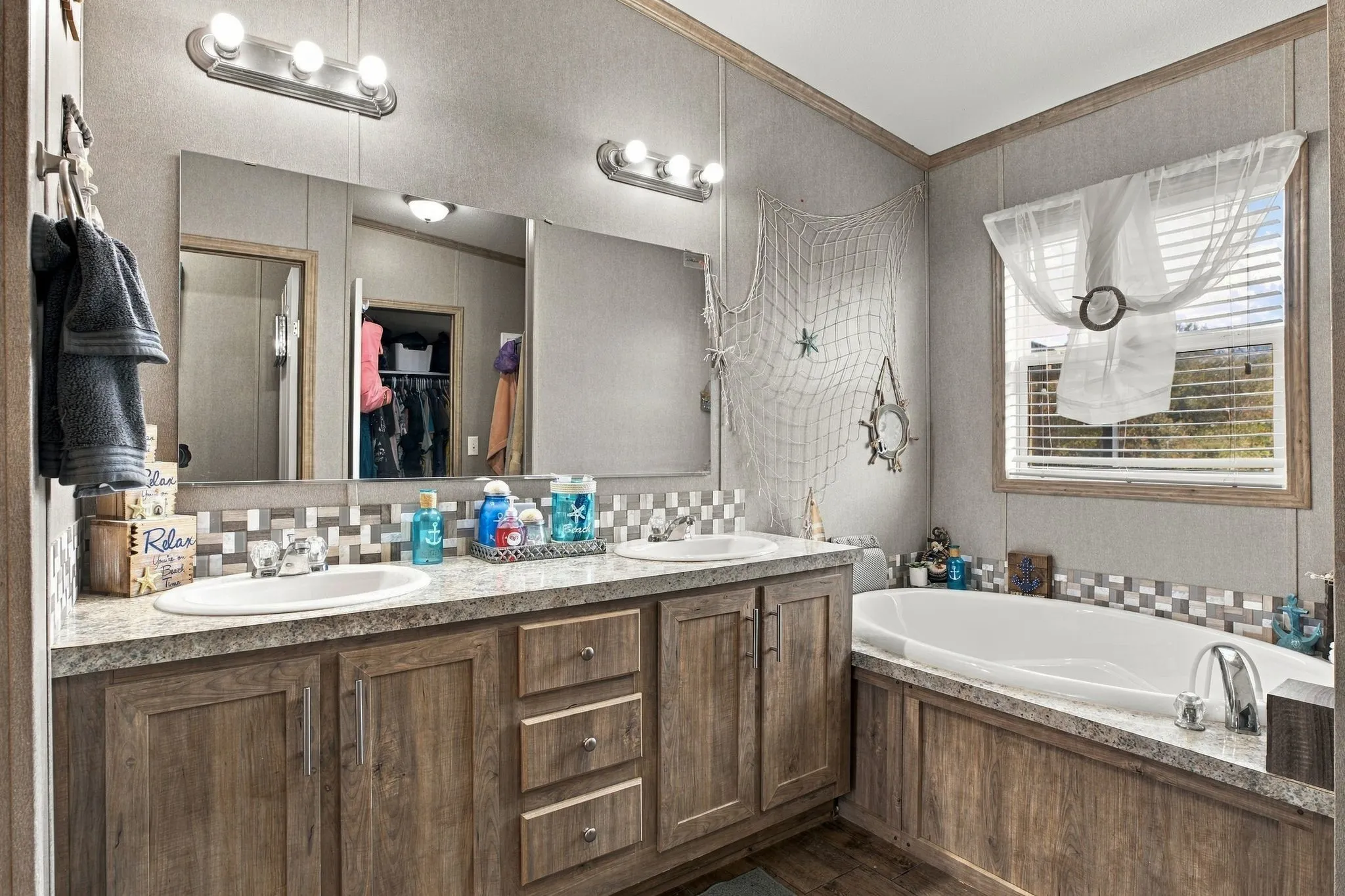 Dual vanity with integrated sinks, wood-finish cabinetry, and mosaic tile backsplash