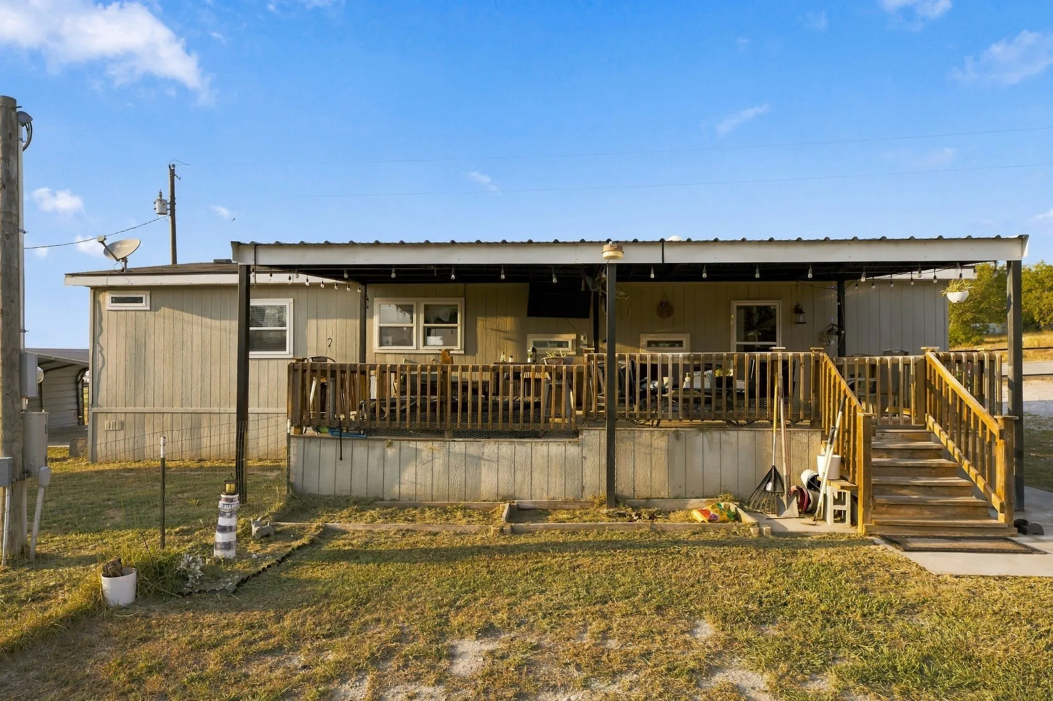 Expansive wooden deck with railing, covered by a metal patio roof, and accessible via wooden stairs