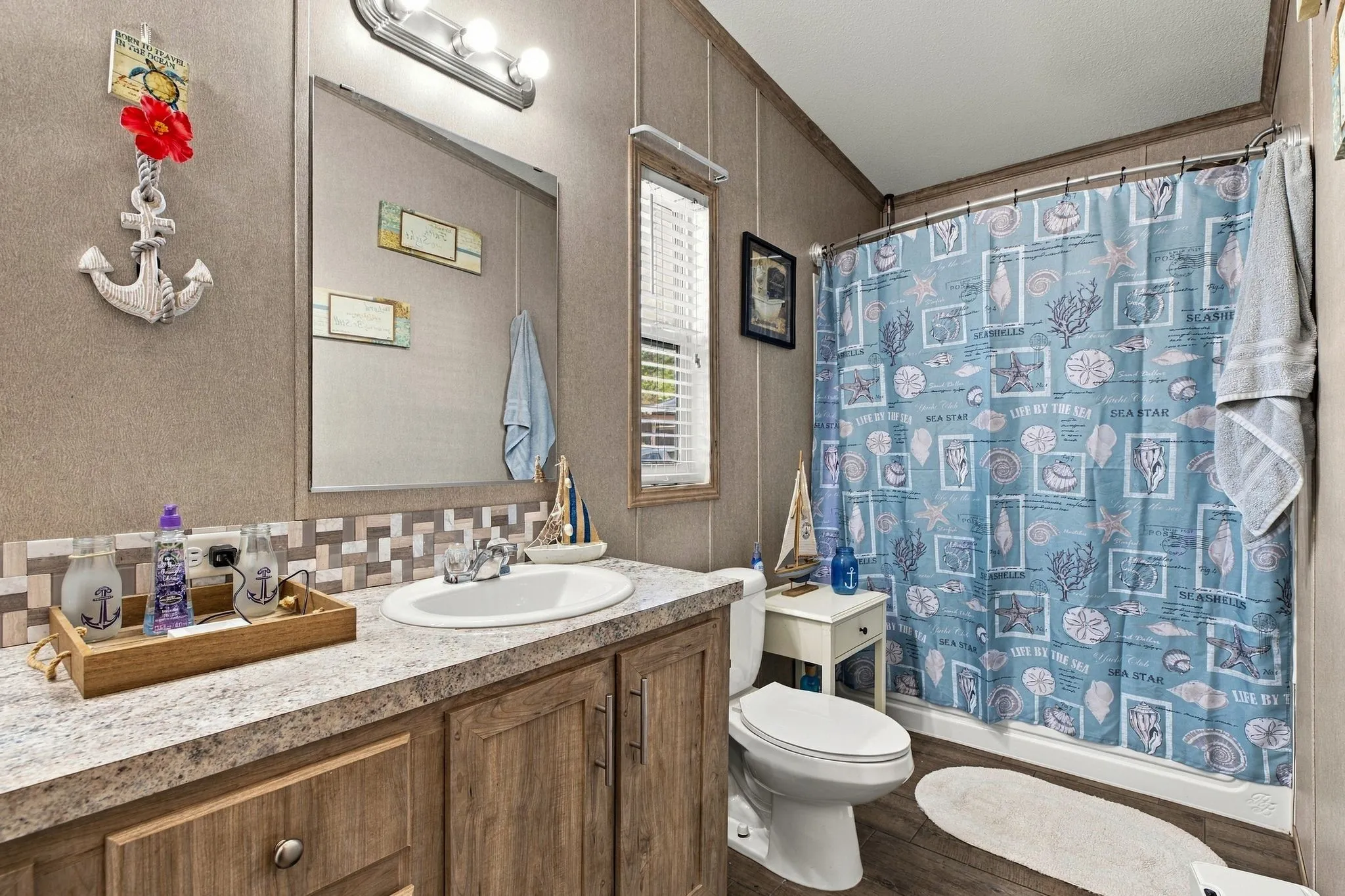 Bathroom featuring a single vanity with a white sink, wood-finish cabinetry, and a shower-tub combination