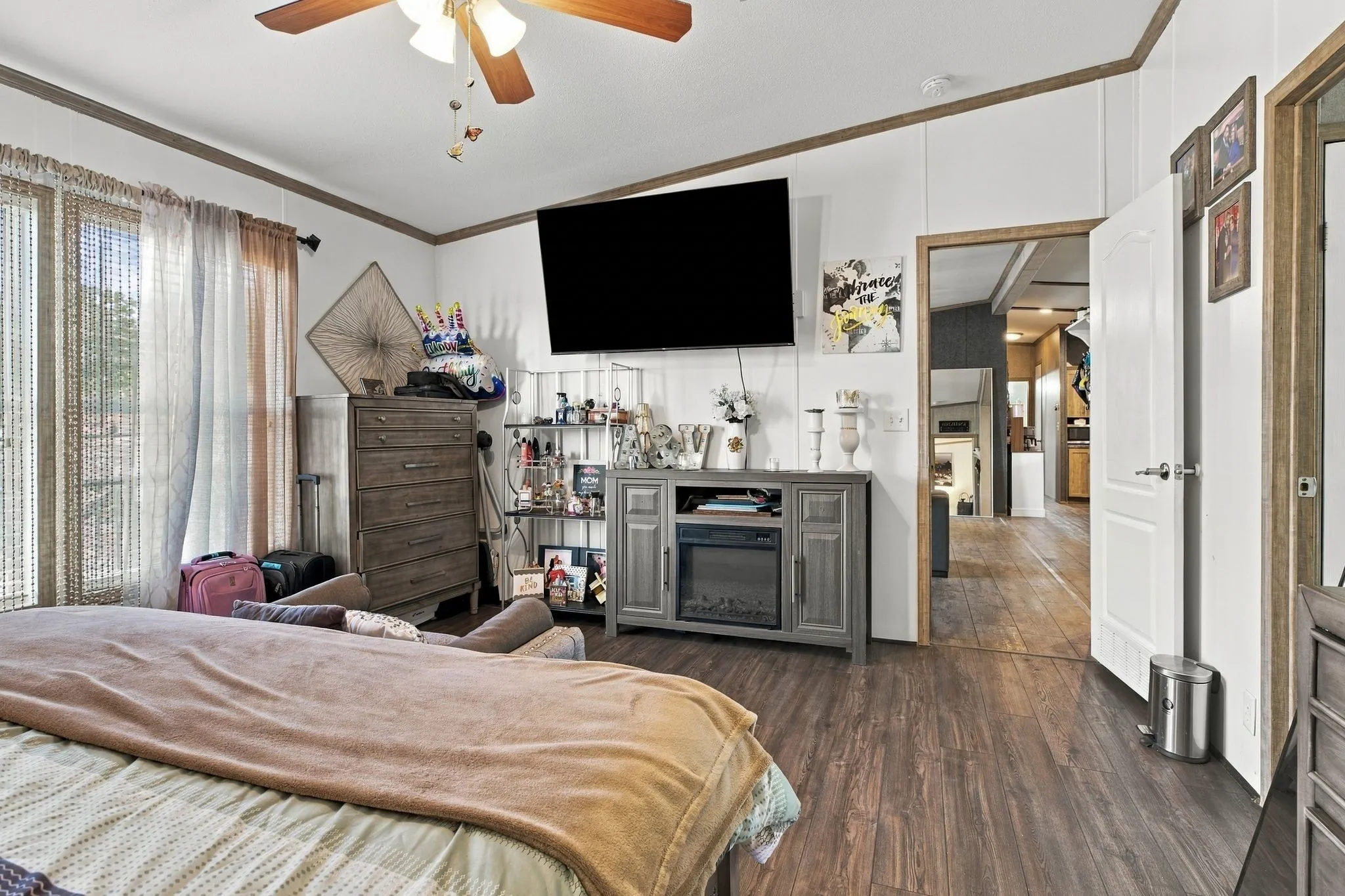 Wood-finish flooring, ceiling fan with integrated lighting, white paneling, and brown trim details