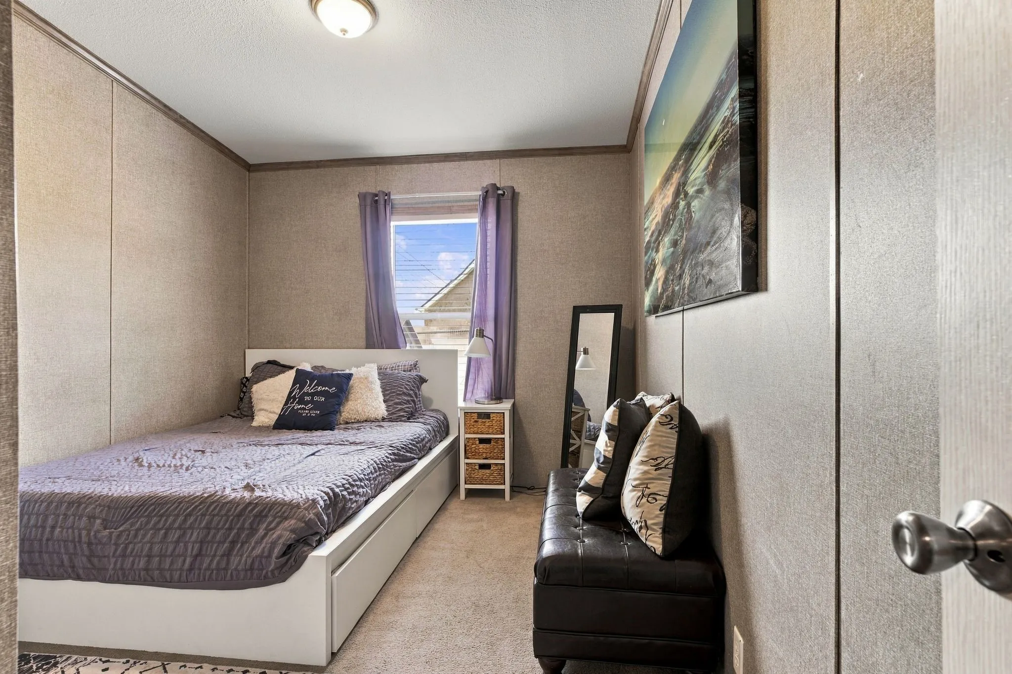 Recessed window with drapes, wall-mounted light fixture, and light-toned wall paneling