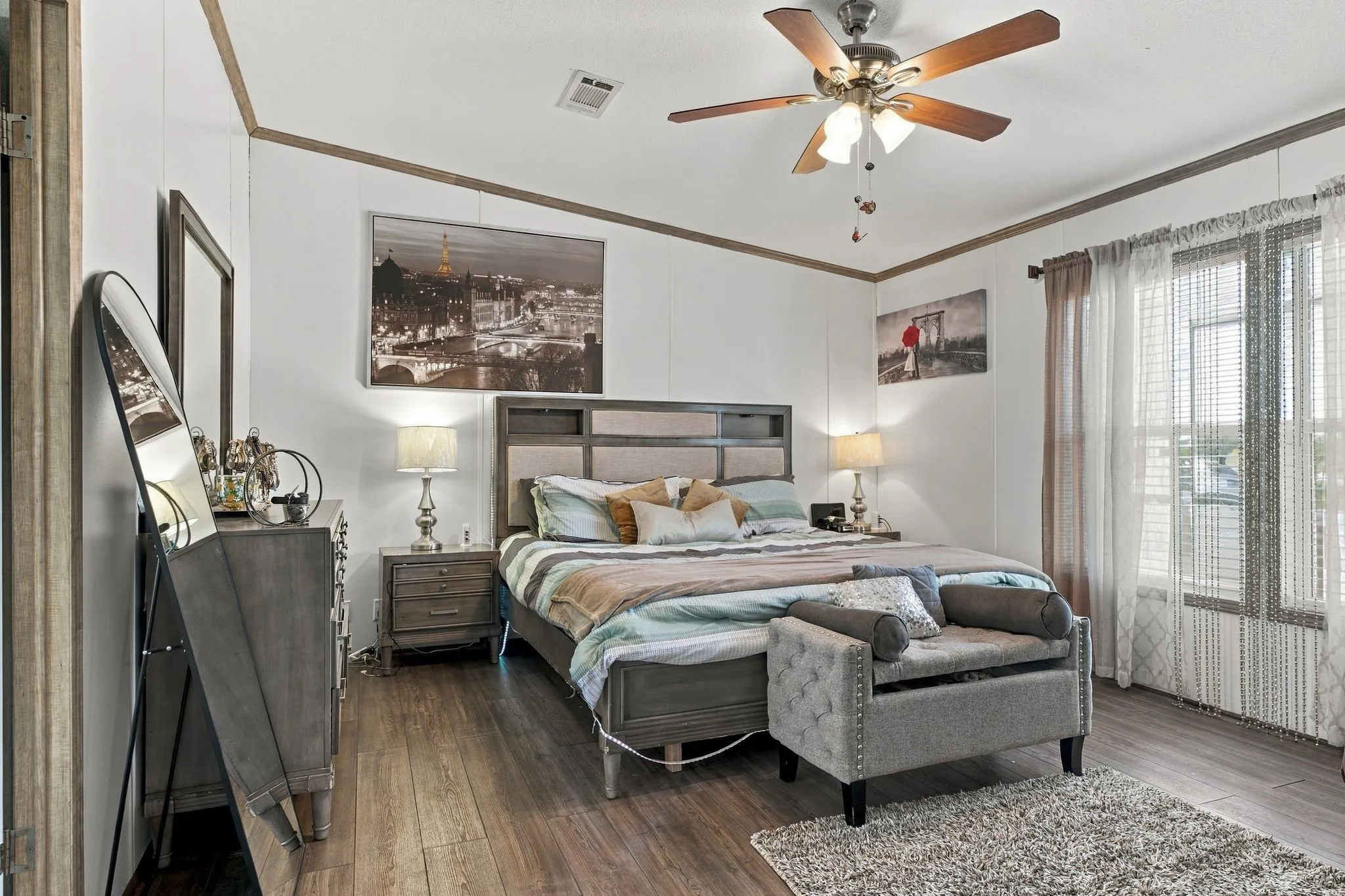 White walls with wood trim accents, wood-finish flooring, a ceiling fan with integrated lighting, and multiple windows with vertical blinds
