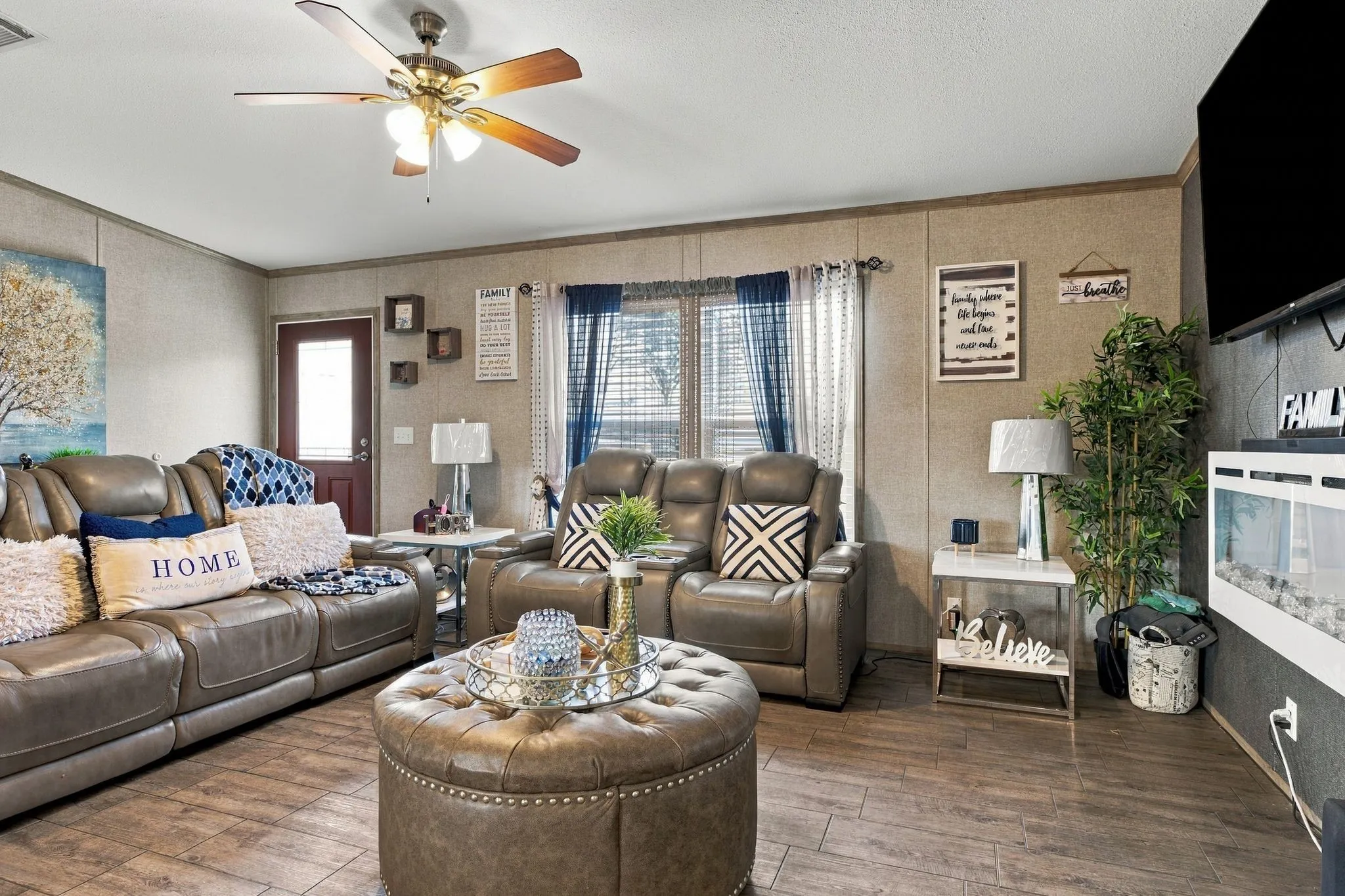 Wood-finish flooring throughout, ceiling fan with integrated lighting, and a white electric fireplace
