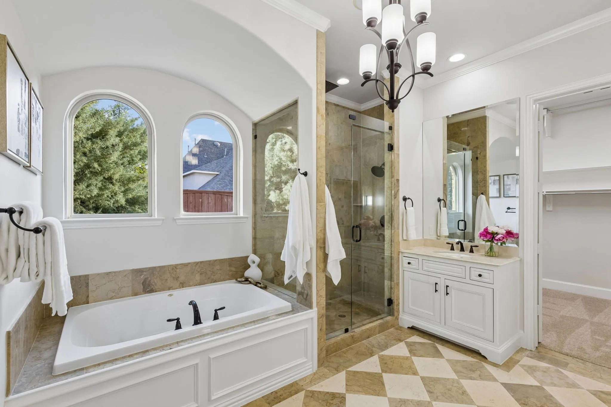 Primary bathroom with separate spa bath and shower. Arched windows bring in plenty of natural light