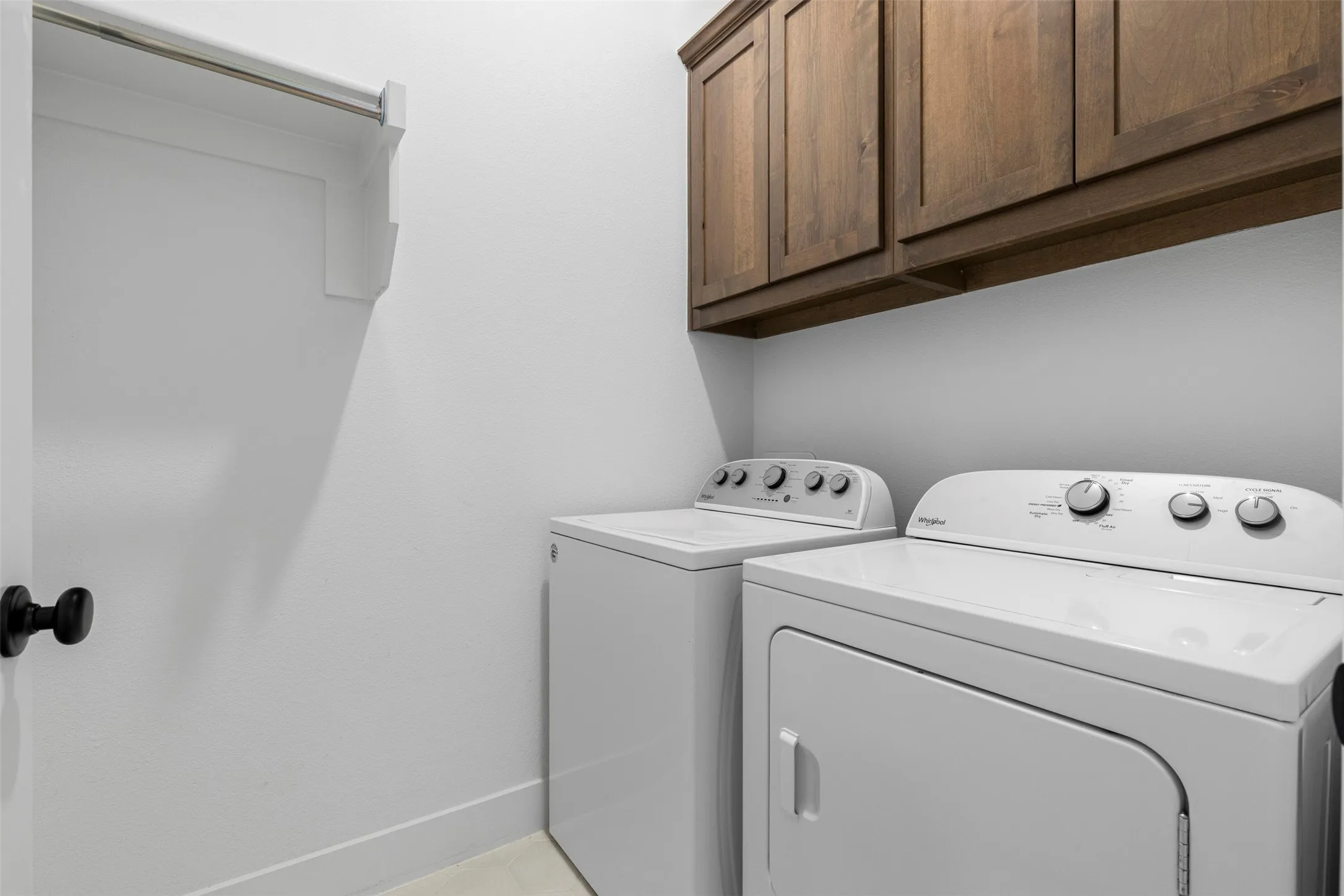 Built-in wood-finish cabinetry, white washer and dryer units, and a closet with a hanging rod