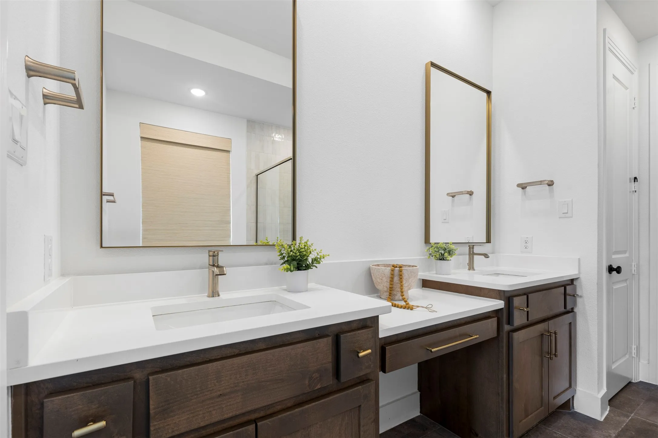 Dual vanities with white countertops, dark wood cabinetry, and gold-finish hardware