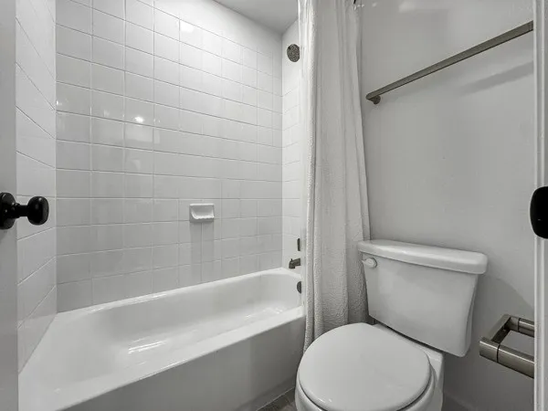 White subway tile shower surround, integrated bathtub, and white toilet