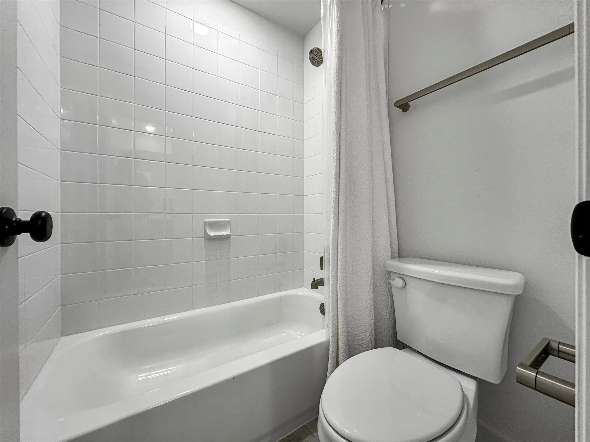 White subway tile shower surround with a built-in tub, toilet, and brushed nickel fixtures