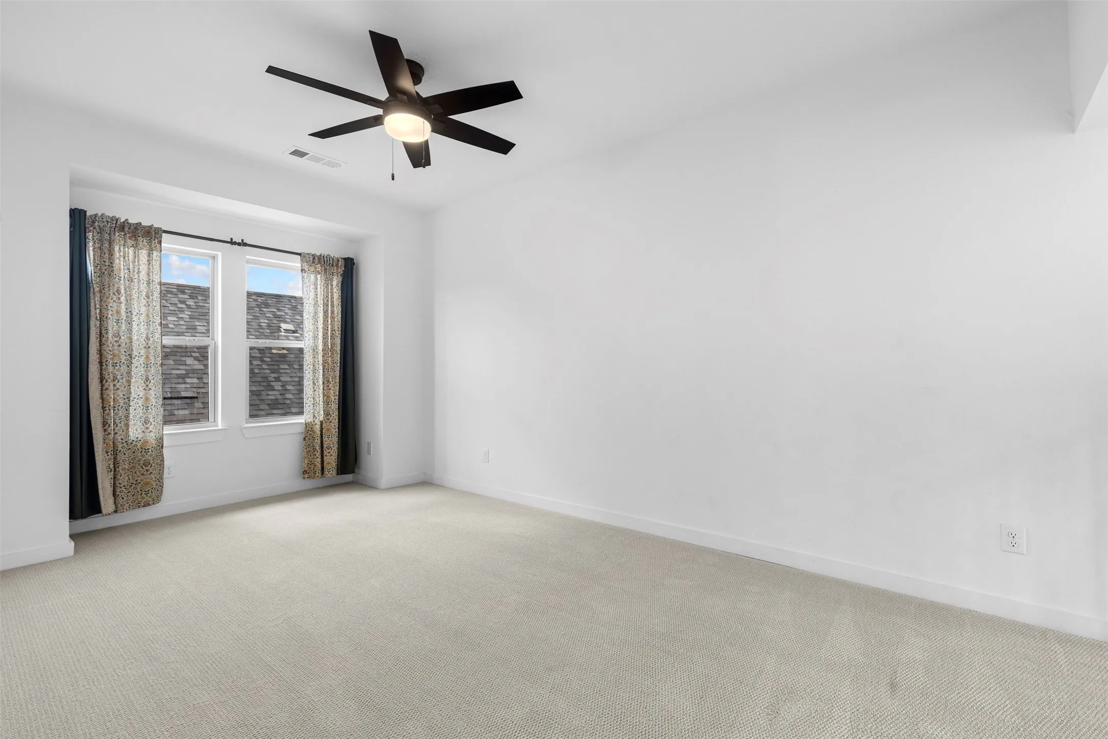 Recessed window area with dual windows, neutral carpeting, and a ceiling fan with integrated lighting