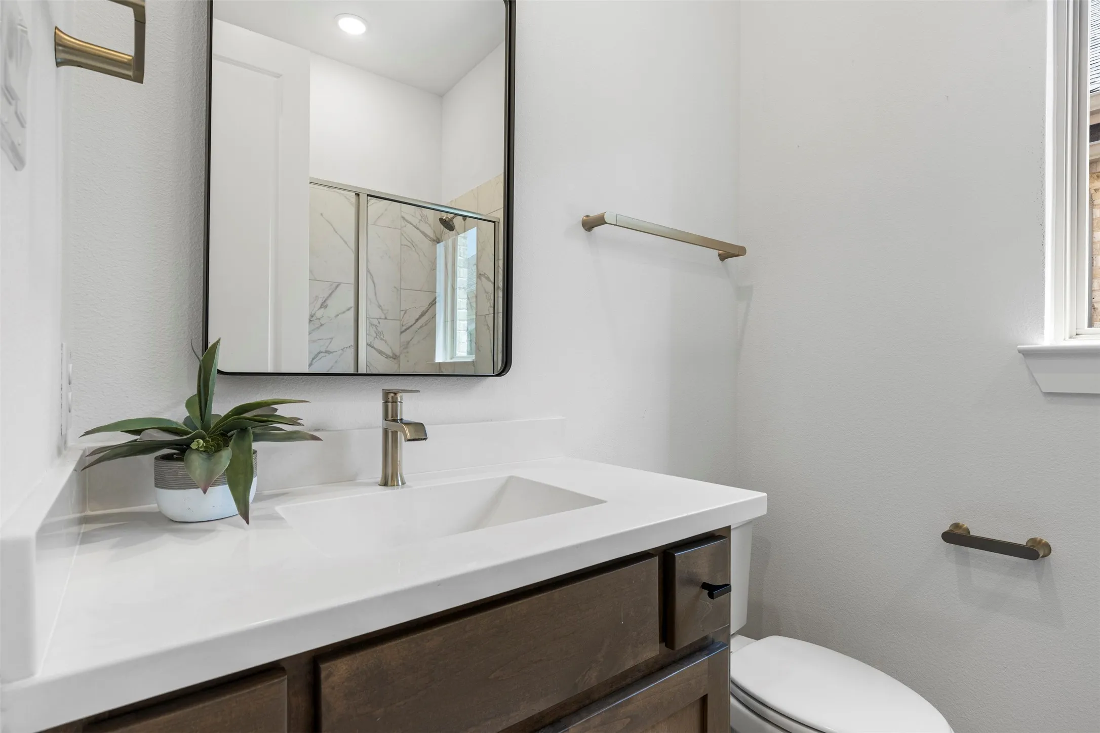 Floating vanity with a white countertop and integrated sink, brushed nickel faucet, and a black-framed rectangular mirror