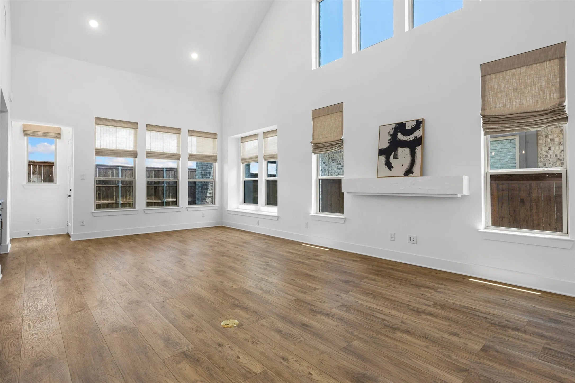 Vaulted ceiling, wood-finish flooring, recessed lighting, multiple windows with natural light, and a floating wall shelf