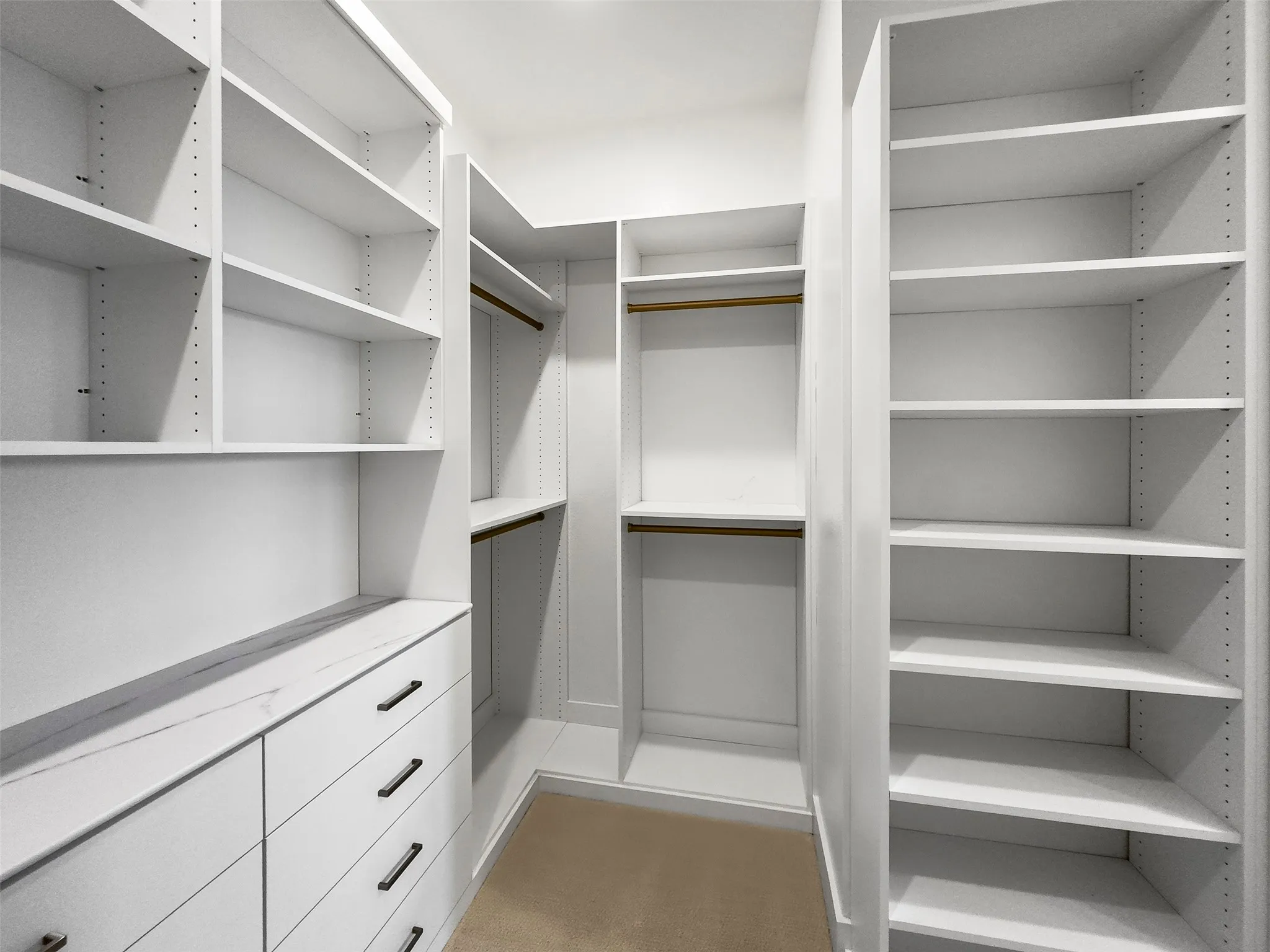 Built-in closet system with adjustable shelving, integrated drawers featuring dark hardware, and hanging rods