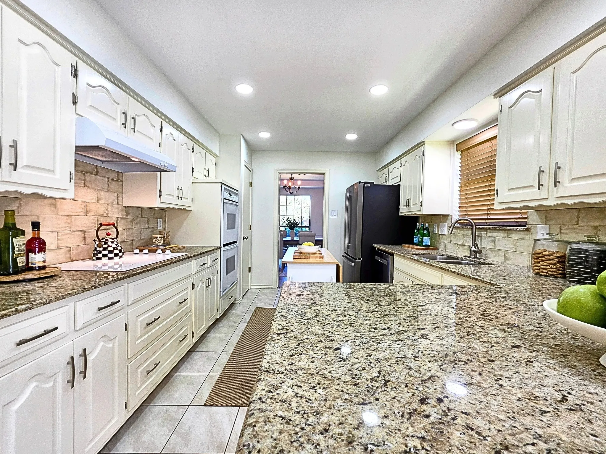 Kitchen featuring granite countertops, white cabinetry, a tile backsplash, recessed lighting, and tile flooring