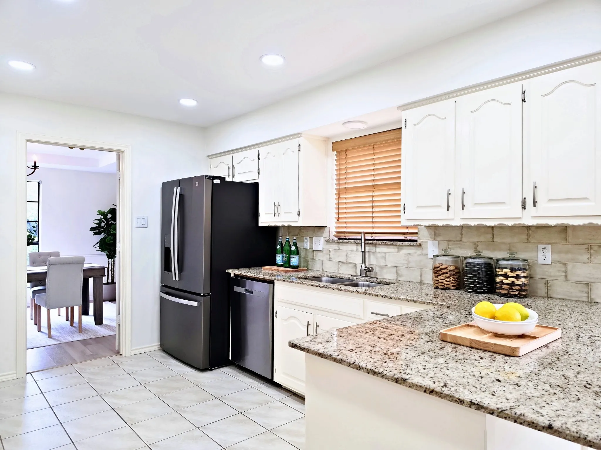 Kitchen featuring white shaker-style cabinetry, granite countertops, tile flooring, and a tile backsplash