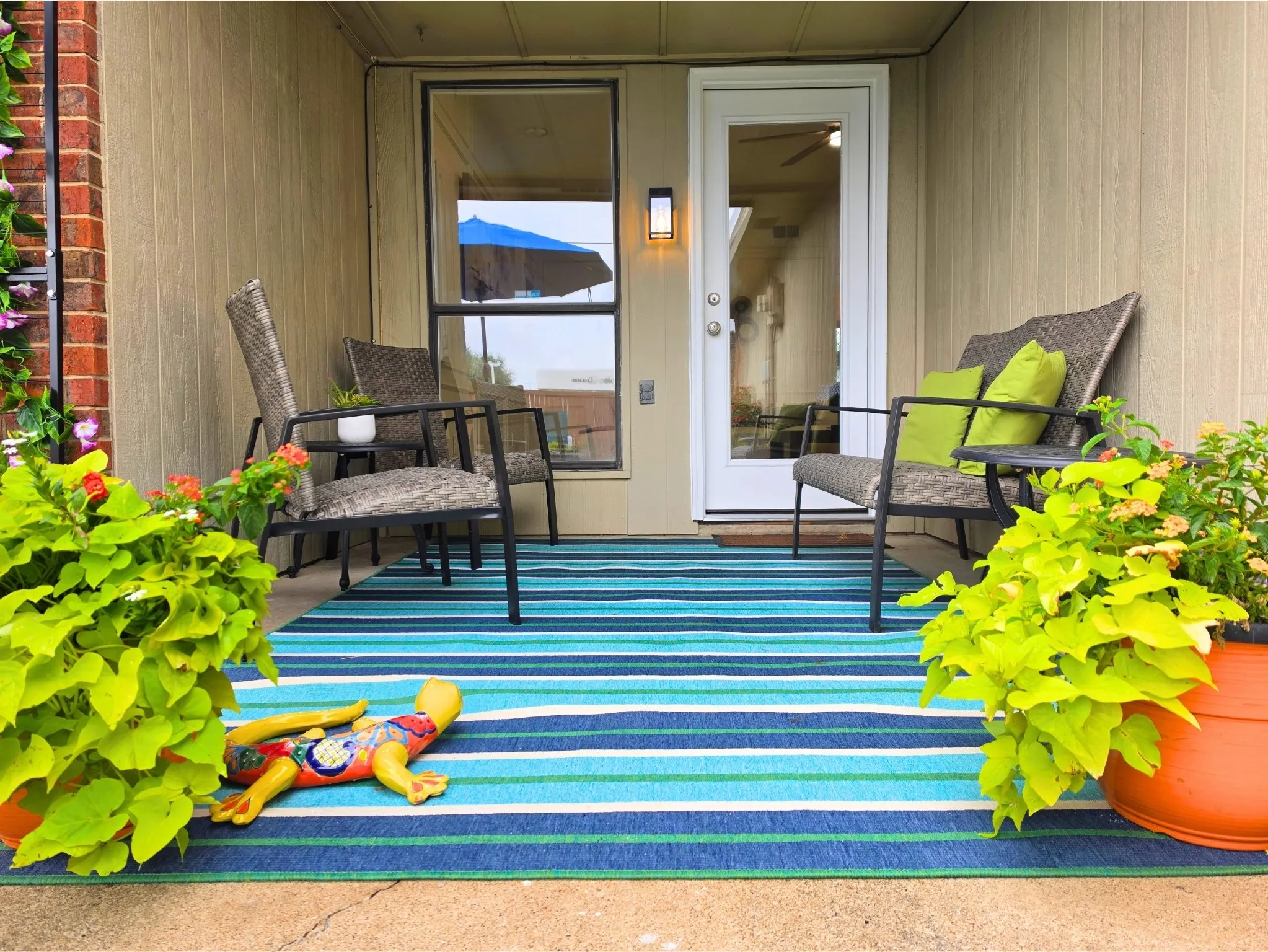 Covered patio with a brick column accent, board and batten siding, and a full-light entry door