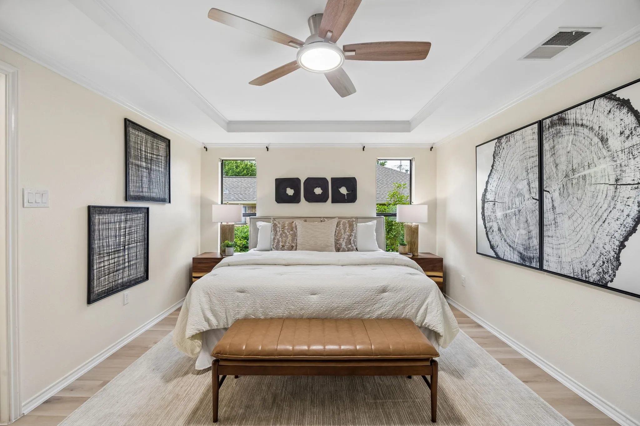 Tray ceiling with crown molding, ceiling fan with integrated lighting, wood-finish flooring, recessed windows, and neutral wall tones