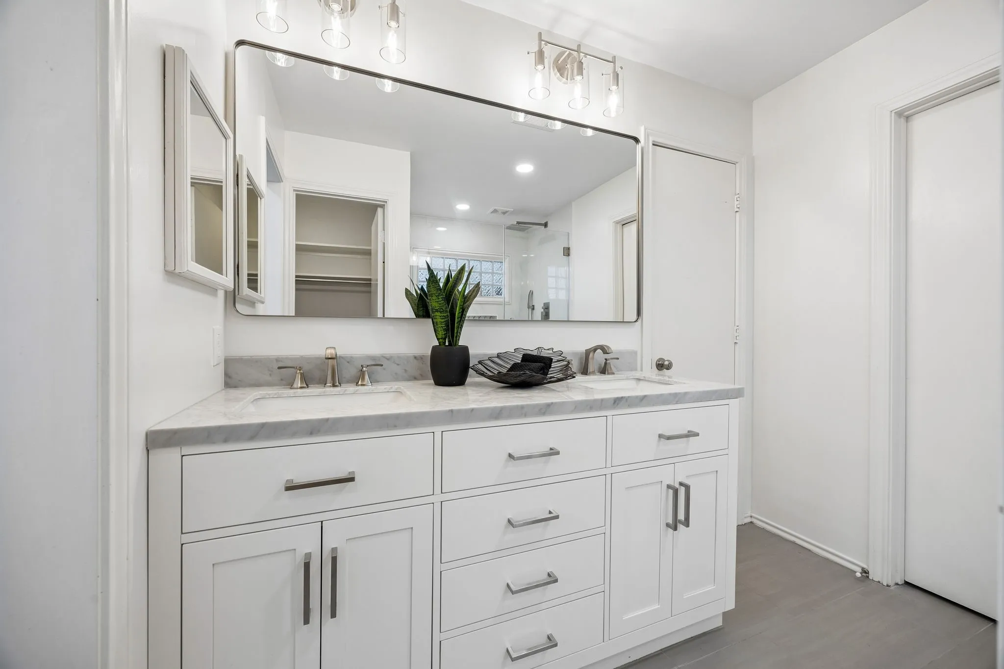 Dual vanity with white cabinetry, integrated sinks, a stone countertop, and brushed nickel hardware