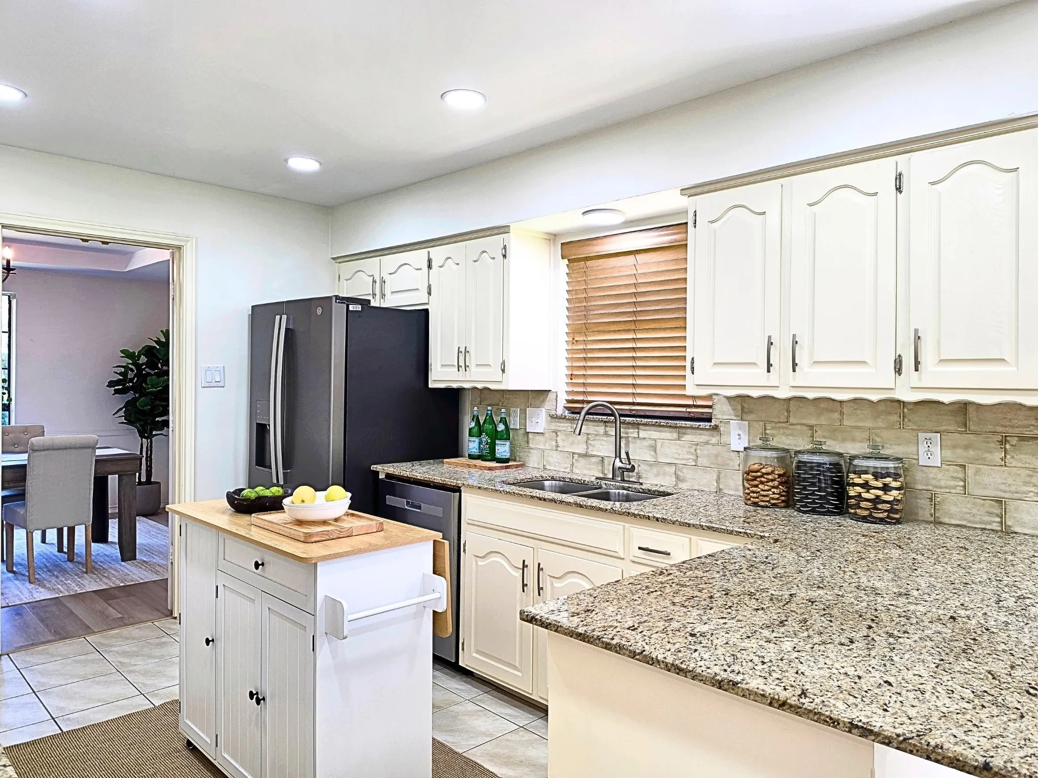 Kitchen featuring granite countertops, a tile backsplash, light-toned cabinetry, and stainless steel appliances