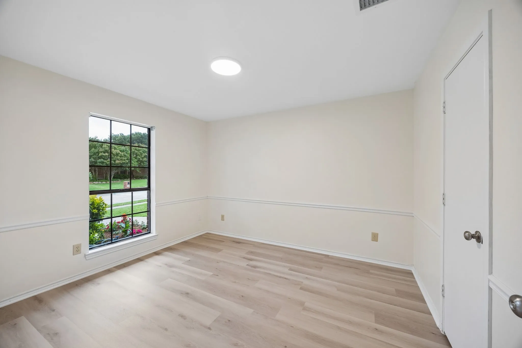 Recessed lighting and a skylight illuminate this space featuring wood-finish flooring, chair rail molding, and a grid-pattern window