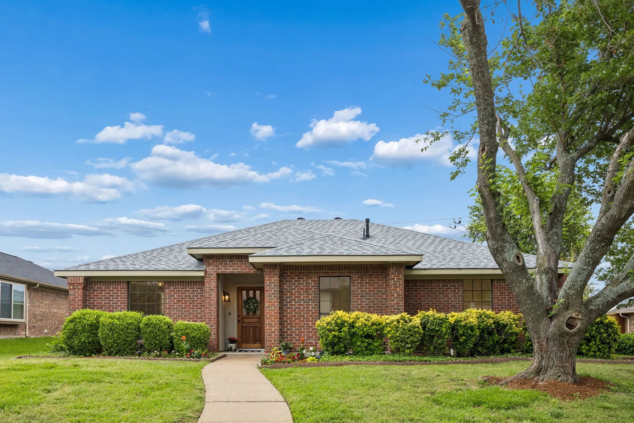Brick exterior with a gray shingle roof and a wooden front door