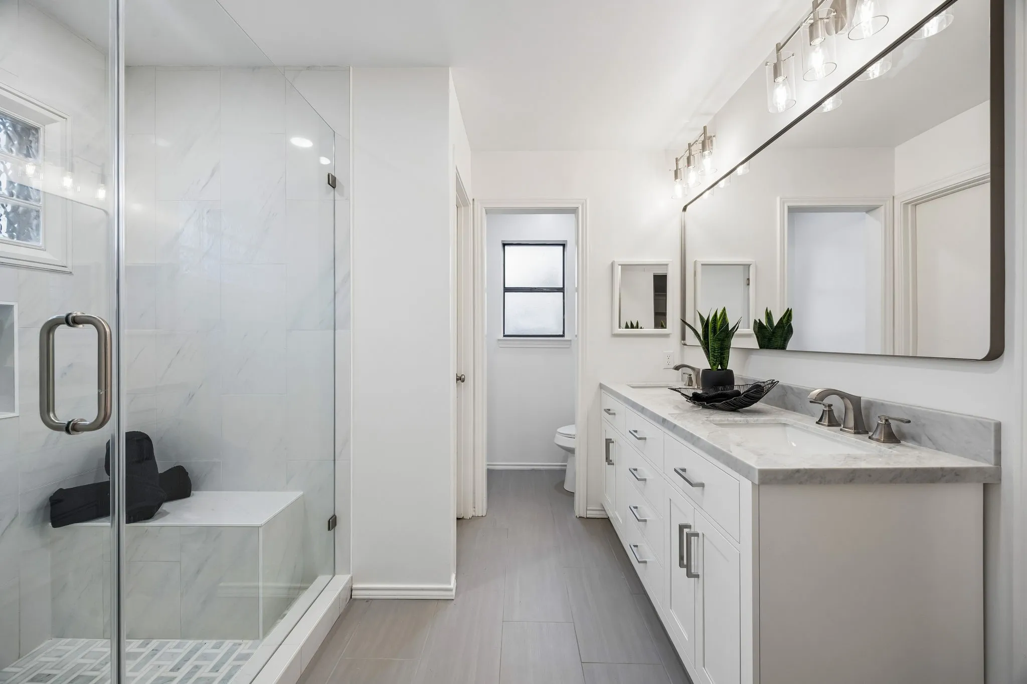 Walk-in shower with clear glass enclosure and built-in bench