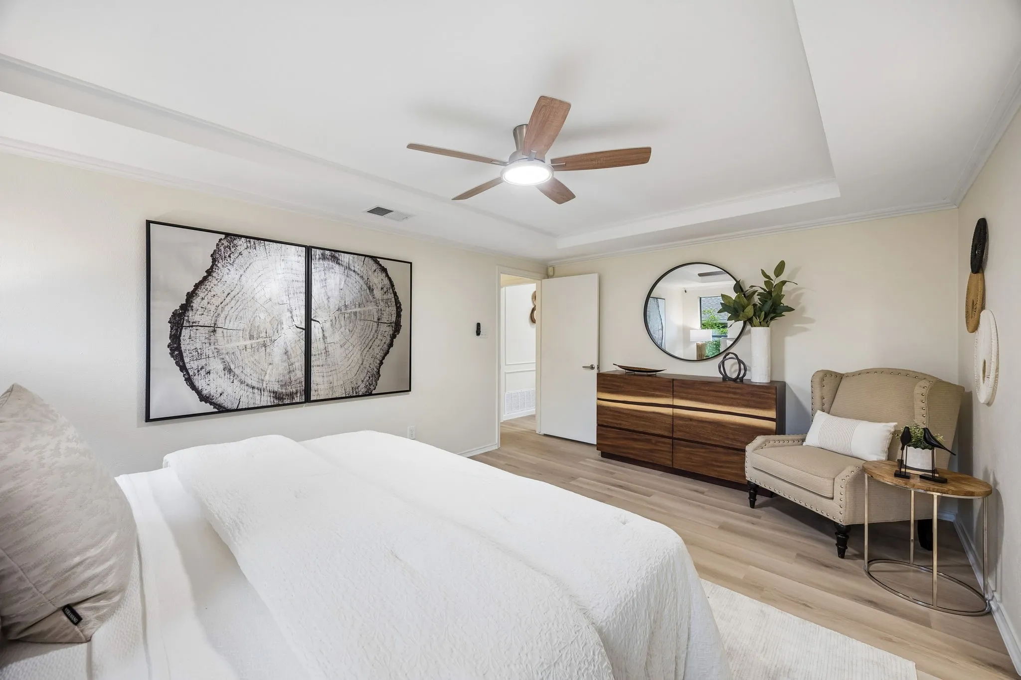 Recessed ceiling with crown molding, wood-finish flooring, and a ceiling fan with integrated lighting